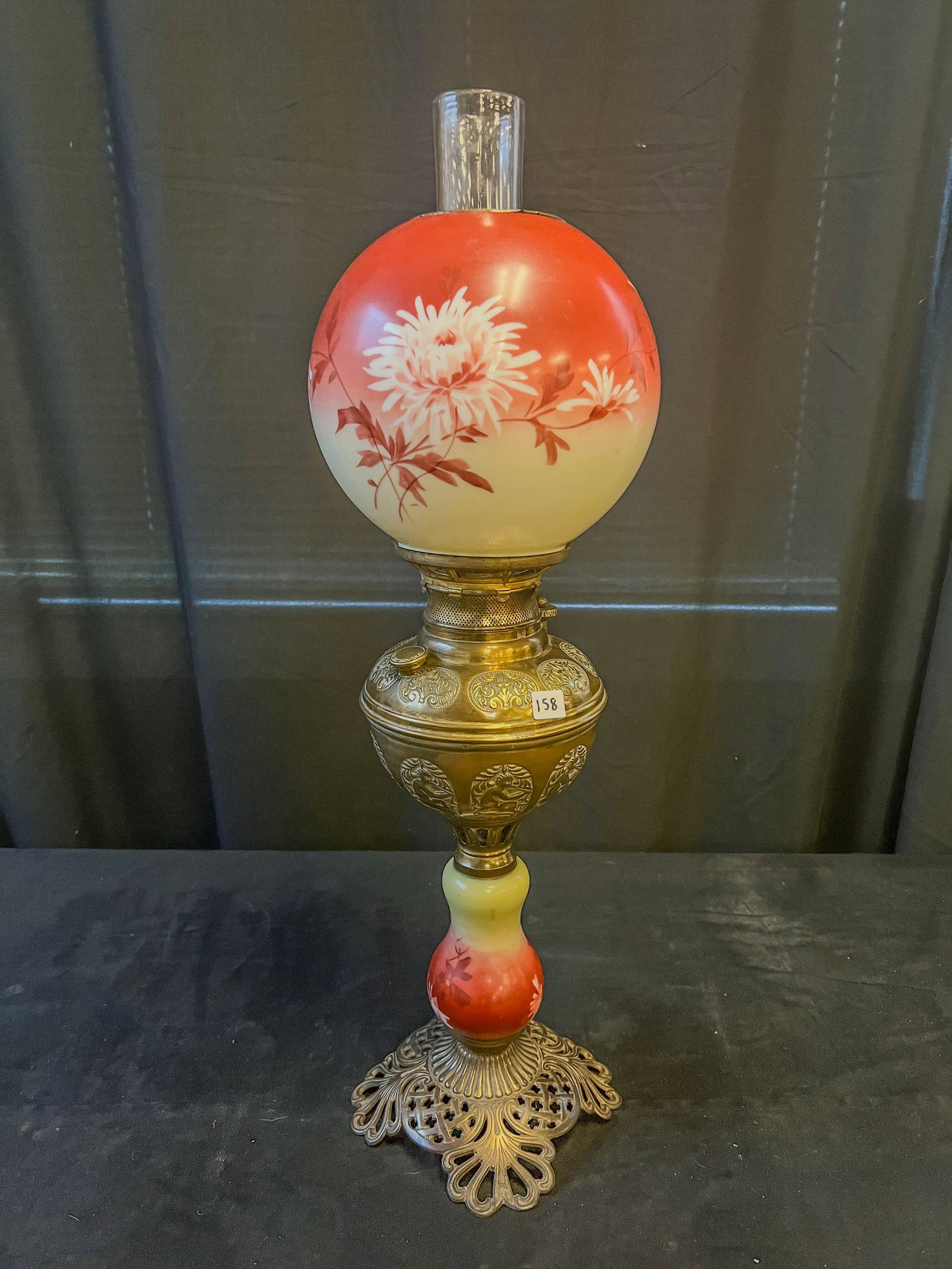 Hand Painted Floral Banquet Oil Lamp: An 1890s hand painted banquet oil lamp. Ball shade and stem feature chrysanthemums, font is embossed with a nude figure playing an instrument. This lamp is an unusual size and in excellent condition, 