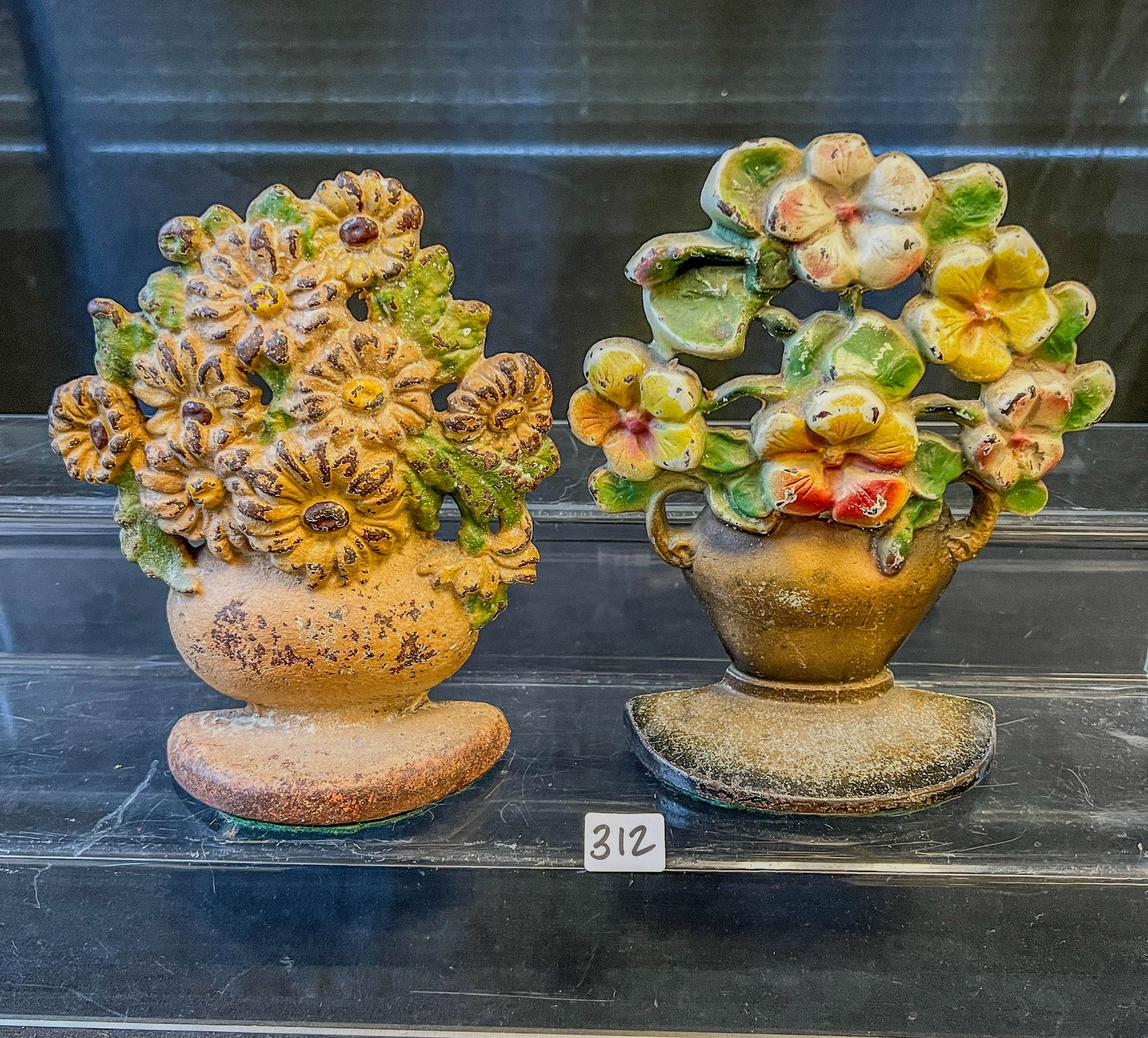 2 Cast Iron Floral Boquet Basket Doorstops c.1900-1920: A pair of Cast iron loral bouquet doorstops with original paint. Minor paint loss noted, consistent with age.