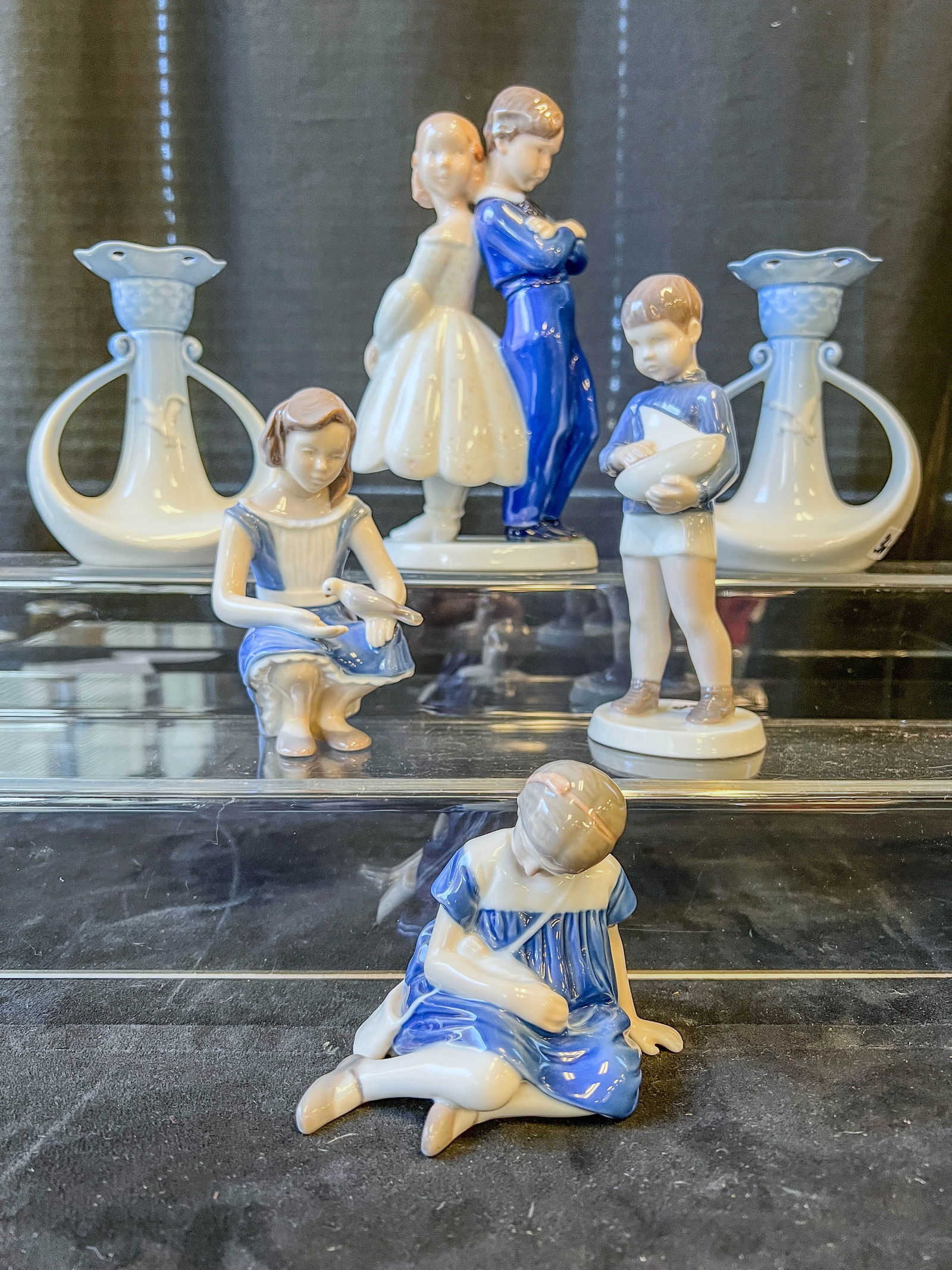 Group of Bing and Grondahl Figurines, Candlesticks: This group of Danish porcelain figurines is by Bing and Grondahl include Boy and Girl first meeting (8" tall), Skipper #2380 (7.25" tall), Girl feeding Dove #2340 (5.5" tall), and Girl with Doll #1526