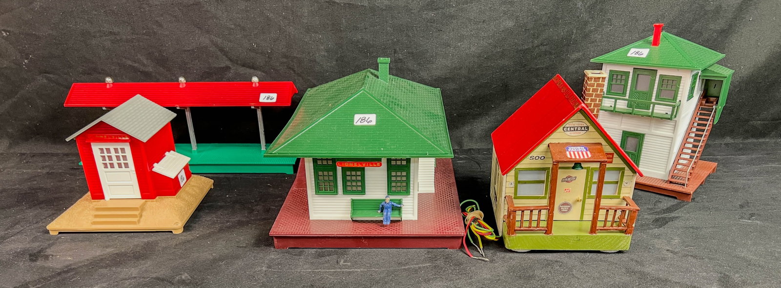 VIntage O Gauge Train Buildings, Folk Art Whistlestation, More!: A Group of vIntage O Gauge train buildings to include a Folk Art wood electrified Whistlestation made in 2016 by Ken Kubiak for his great grandson Winton, a Lionel train platform, a Lionelville electr