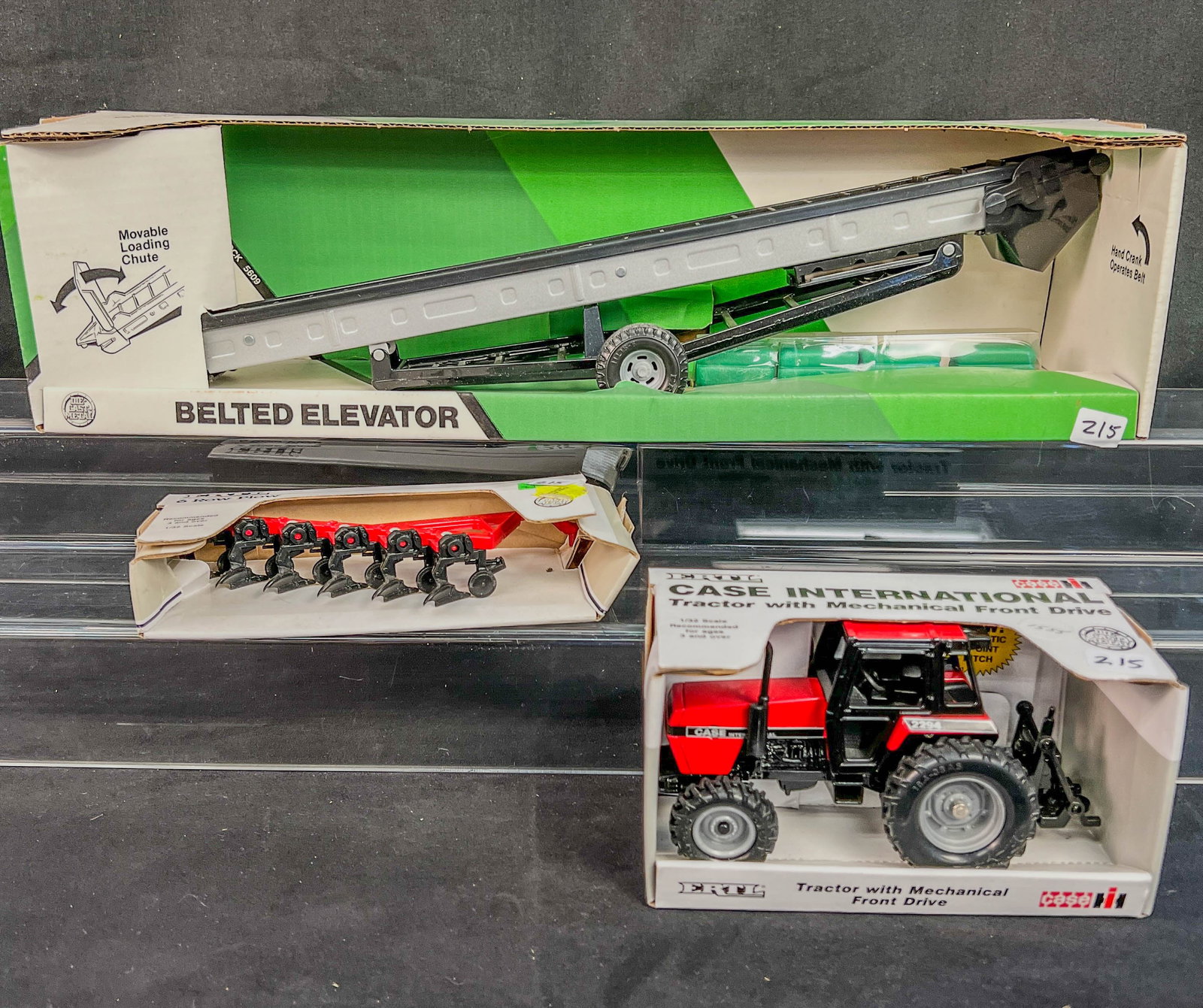 Ertl Die Cast 1/32 Scale Case International Tractor, 6 Row Plow and John Deere 1/16 Scale Belted: Ertl Die Cast 1/32 Scale Case International Tractor, an Ertl 1/32 6 Row Plow and John Deere 1/16 Scale Belted Elevator, all 3 are unused in boxes.