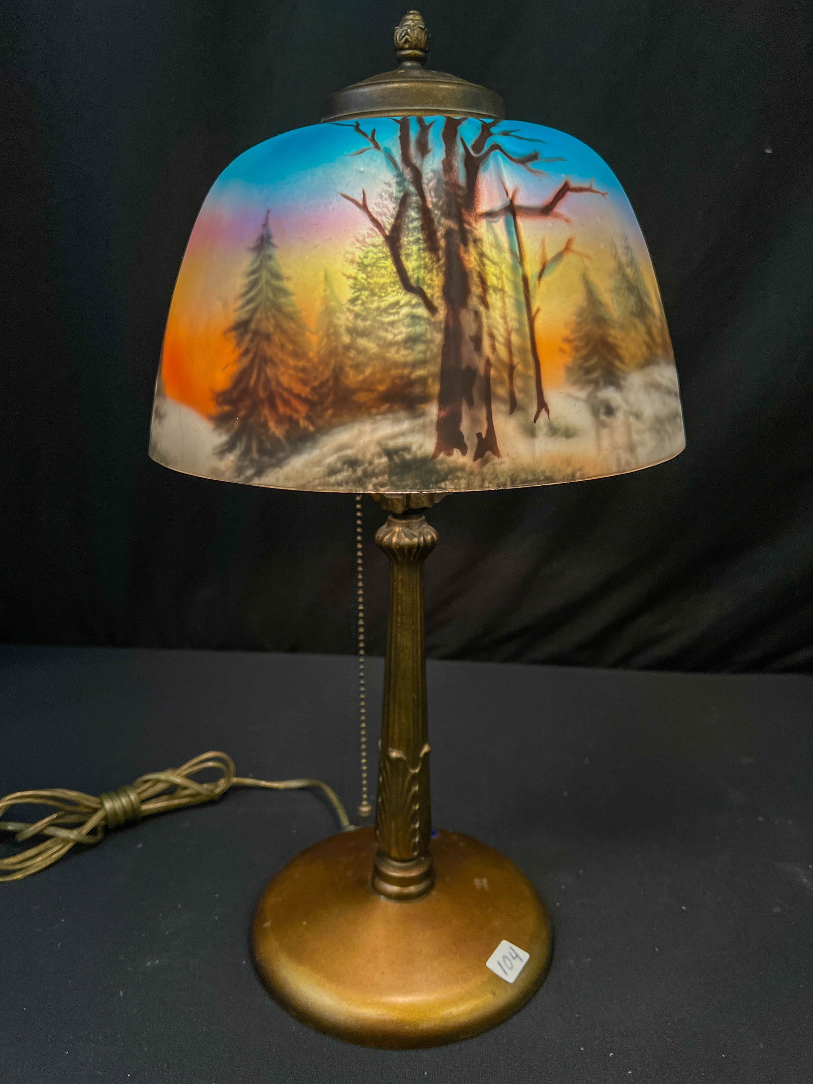 Mission Arts and Crafts Reverse Painted Table Lamp: Mission arts and crafts reverse painted table lamp depicting a well-executed woodland winter scene. In excellent working condition. Retains its original heat cap finial. No chips, cracks, or flea bite