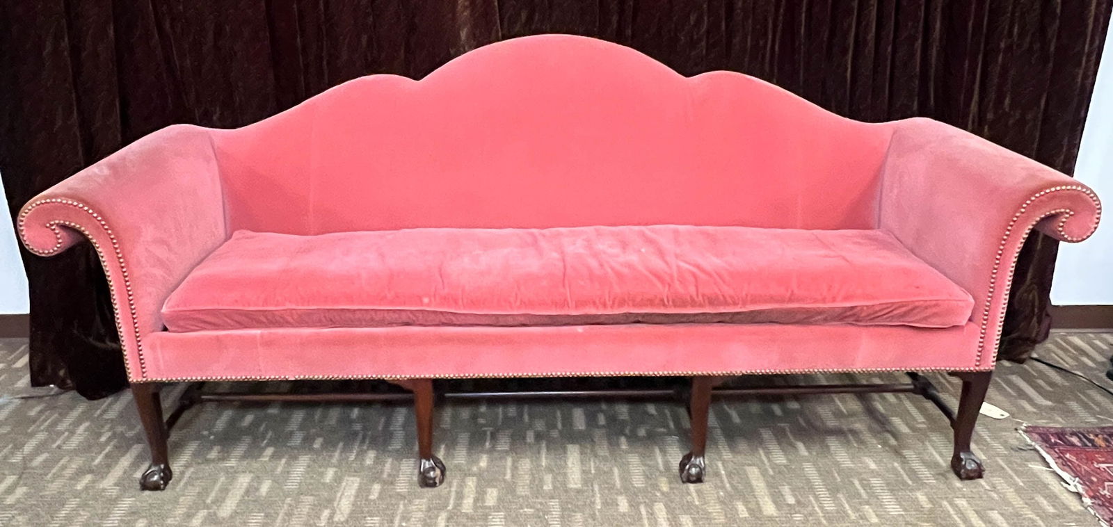 An Exaggerated Camel Back Sofa With Four Mahogany Claw Feet: An exaggerated mahogany camel back sofa with full curved rounded arms. Hand carved ball and claw feet with turned stretcher. Age unknown, but sofa is most likely older than it appears. This couch is i