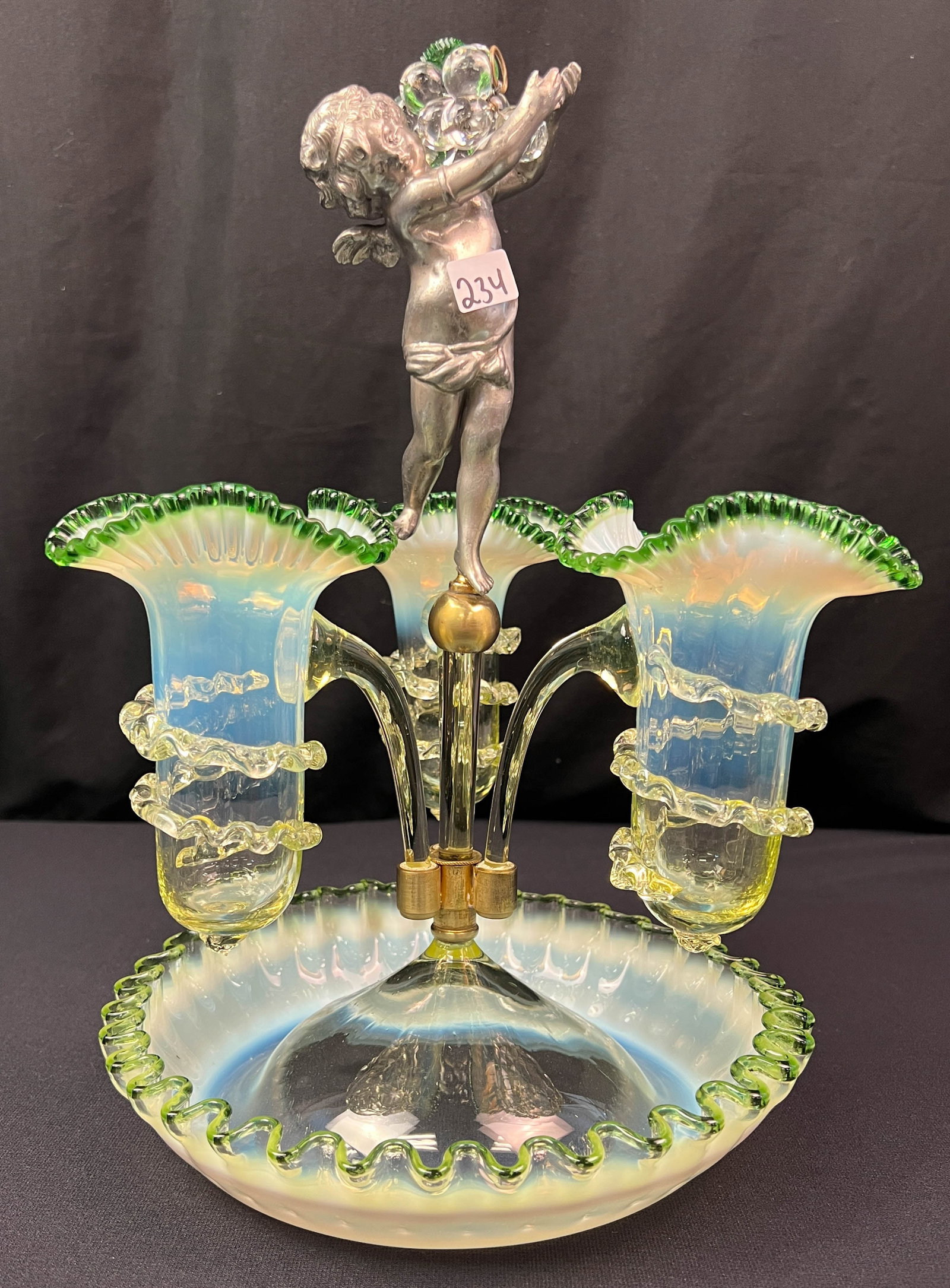 Victorian Epergne Opalescent to Green: An elaborate Victorian epergne that is opalescent to dark green main bowl with three ruffled edge sided flutes finished off with a winged Cupid figure. This unusual epergne is in excellent condition t