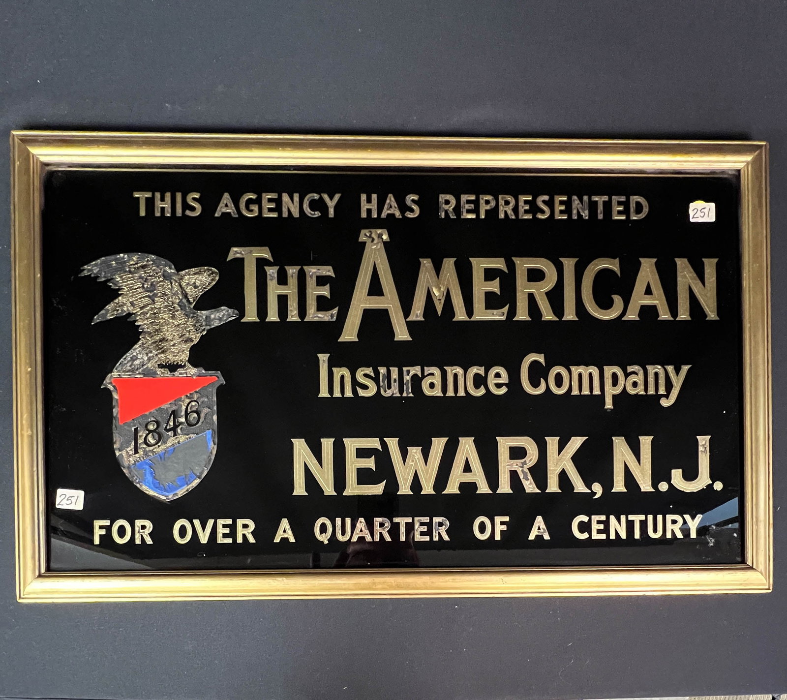 Antique Reverse Painted Advertising Sign for American Insurance Company: An antique reverse painted advertising sign for the American Insurance Company in Newark NJ. Some paint losses noted, measures 15.5" tall X 25.5"across.