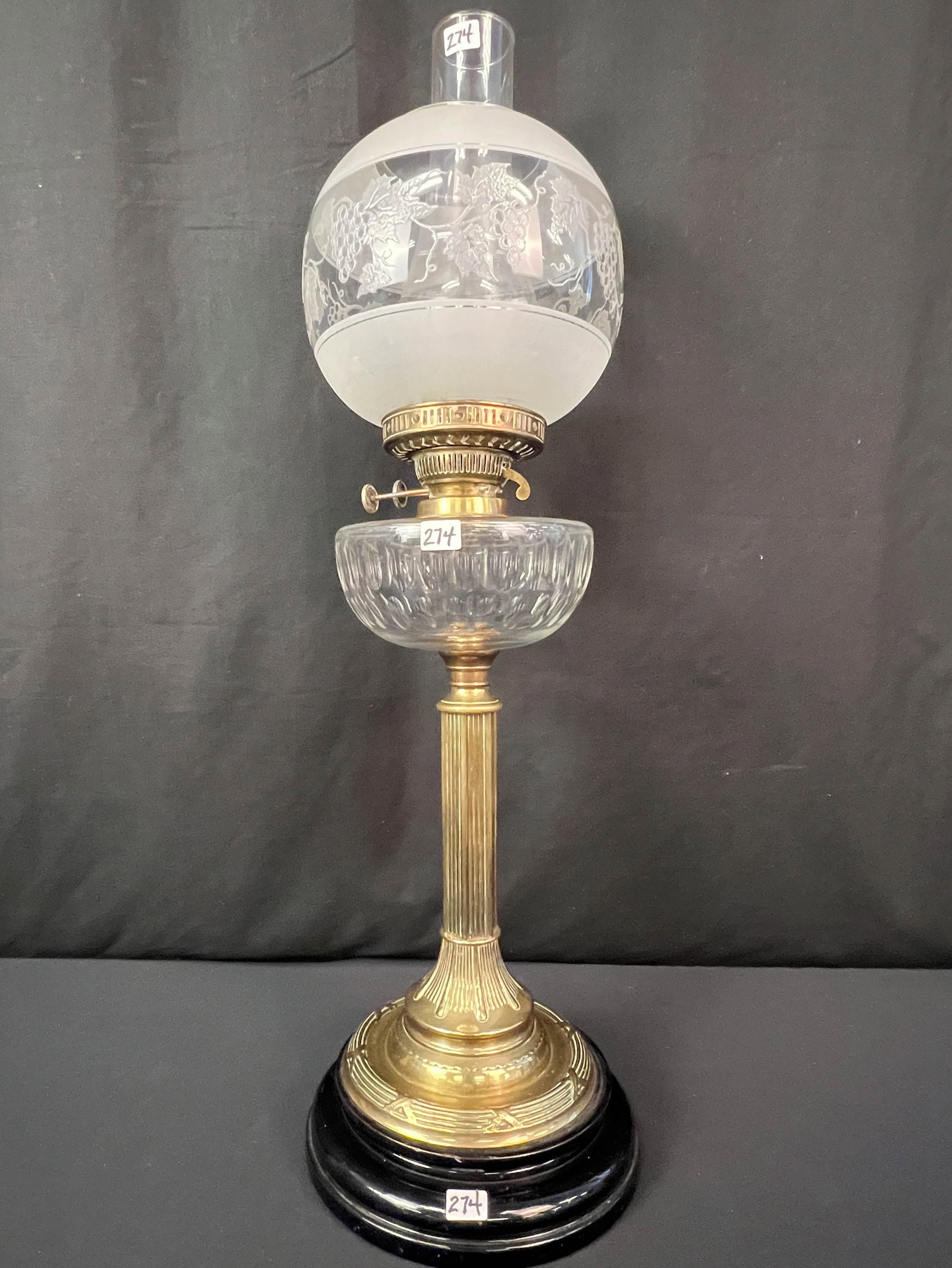 An English Oil Lamp In All Original Condition: An English oil lamp with cut crystal font ball acid cut back vine shade on a brass and black glass base. It is all original and it measures 27" tall.