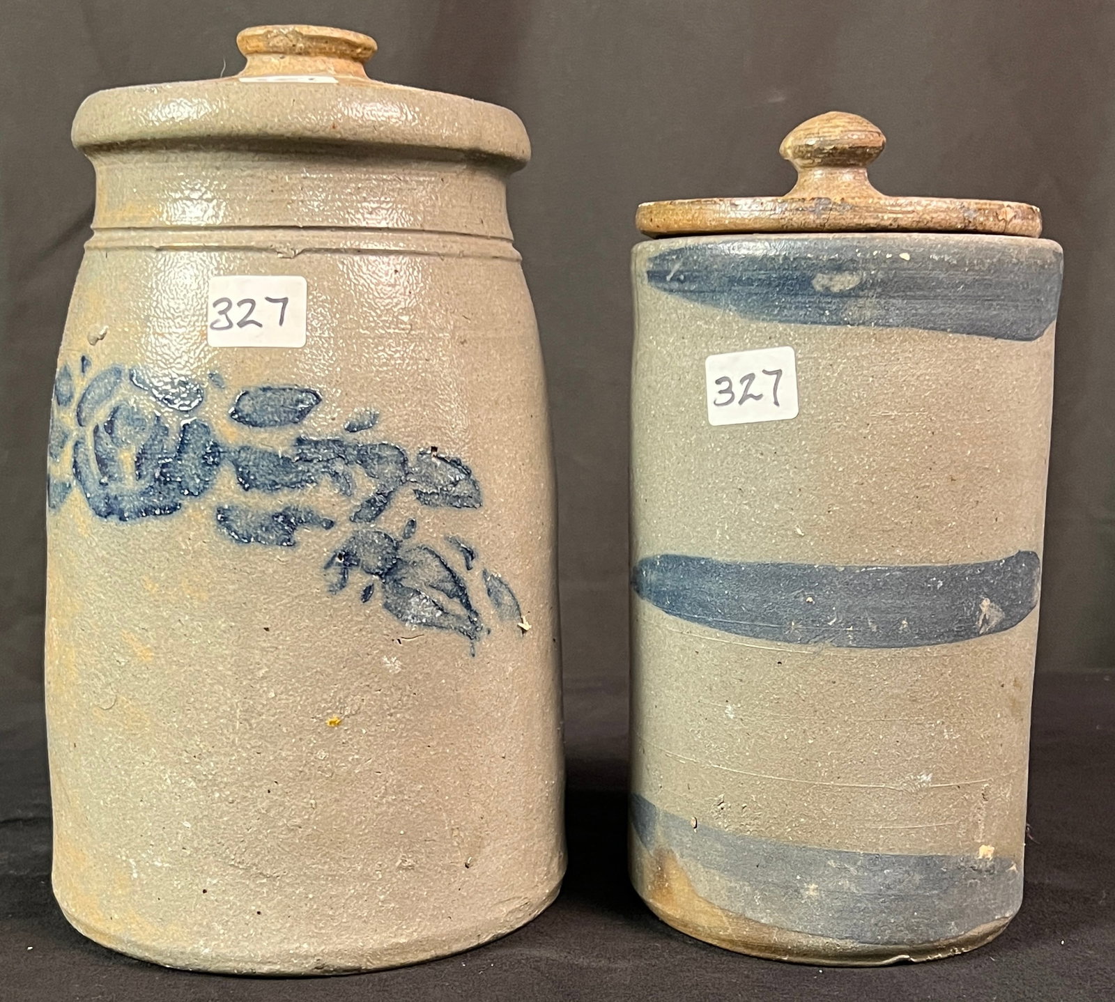 Two Covered and Decorated Stoneware Jars: A salt glaze covered storage jar with floral garland decoration. It measures 8.5" x 5". Along with a salt glaze blue striped decorated storage jar that measures 7" x 4". Both are in very good conditio