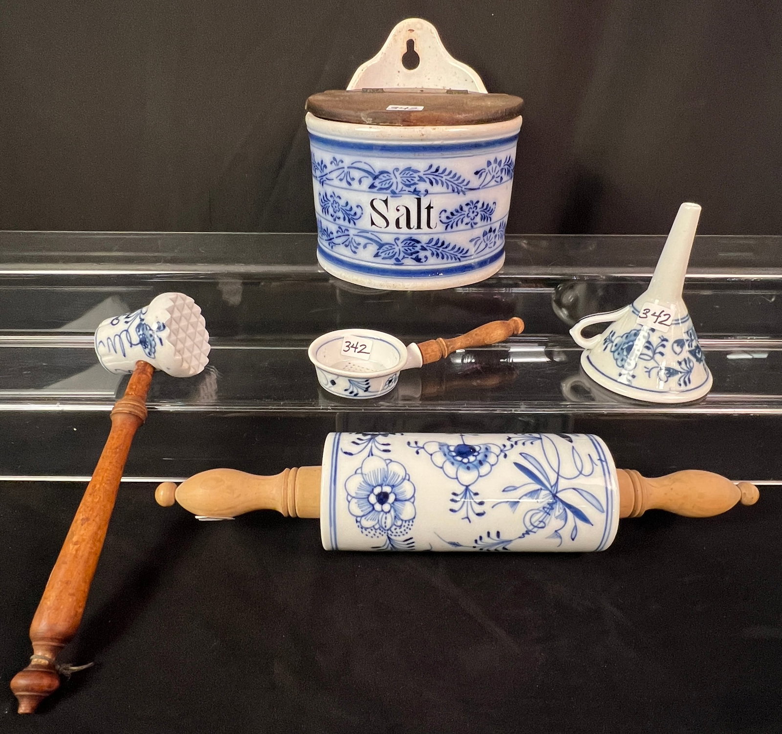 Five Pieces of Blue Onion Kitchenware: Five pieces of Blue Onion kitchenware to include a wall hung salt box that measures 7" tall x 6" wide x 6" deep, a rolling pin that measures 15" long, a masher or meat tenderizer that measures 10" lon