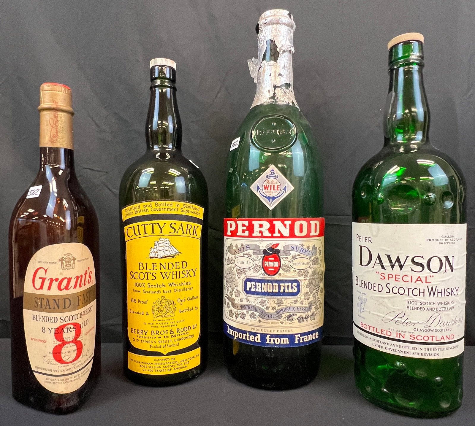 Four Large Display Liquor Bottles: A collection of four large display alcohol bottles to include a Cutty Shark Blended Scots Whisky that measures 19" tall, a Pernod Fils bottle that measures 21.5" tall , a Dawson "Special" Blended Scot