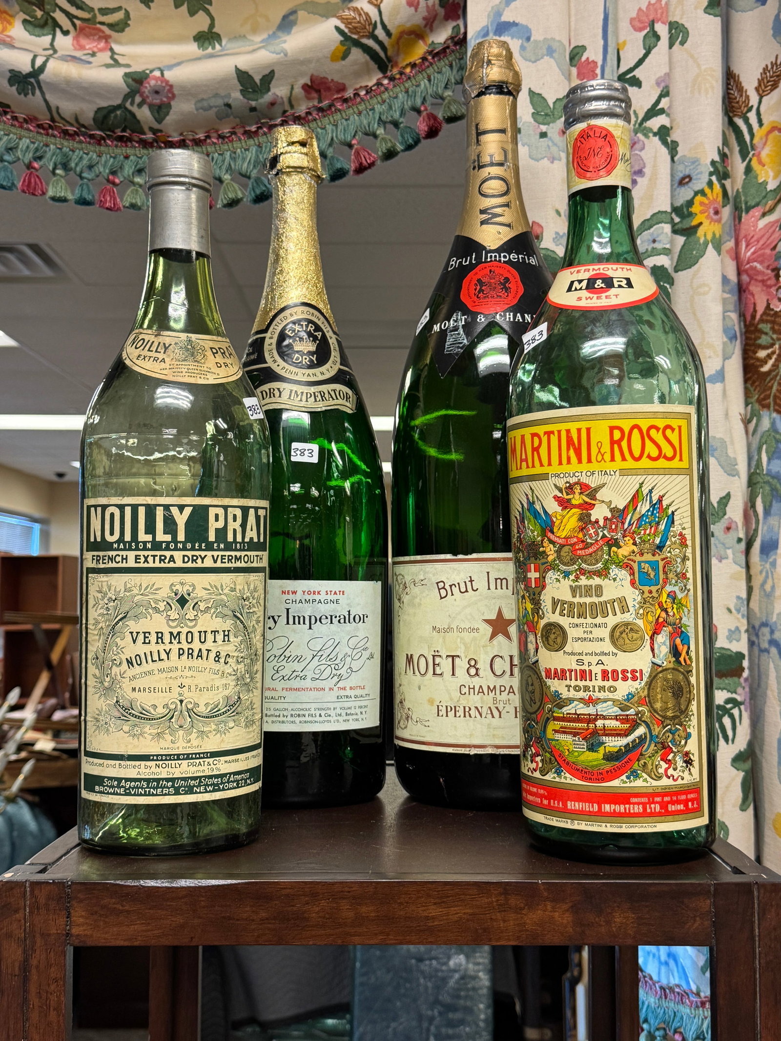 Four Large Display Liquor Bottles: A collection of four large display liquor bottles to include a Brut Imperial Moët & Chandon Champagne display bottle that measures 26.5" tall, a Vermouth Noilly Prat & C. Marseille display bottle tha
