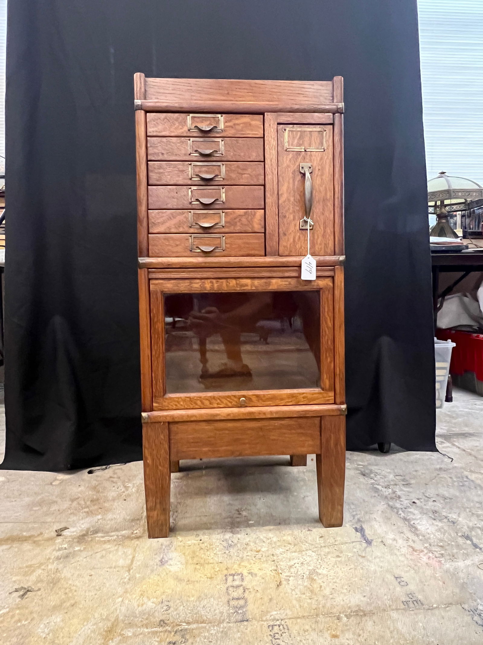 An Oak Miniature Stacking Bookcase/Filing Cabinet: A turn of the century oak miniature four part stacking bookcase/filing cabinet consisting of an oak base, oak glass door bookcase section, six flat drawers, one pullout drawer section, and an oak top.