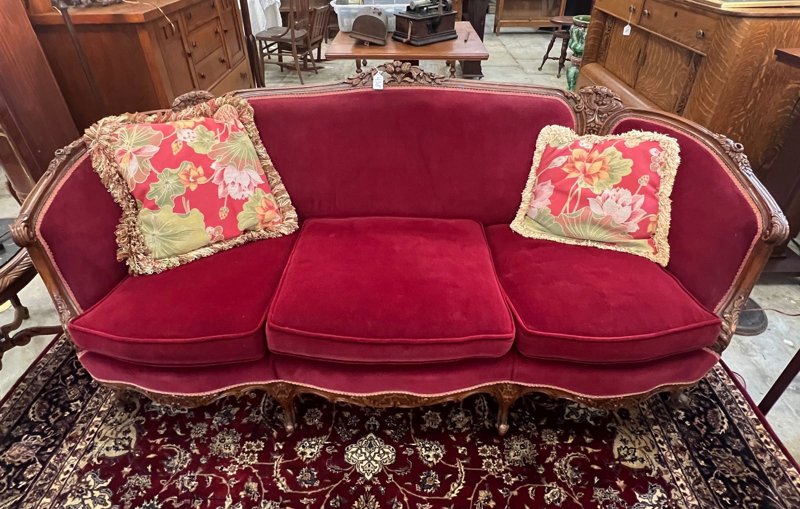 A 1920's Pierced and Floral Carved Sofa: A 1920's pierced and floral carved sofa with newly upholstered in maroon and it is in a mahogany frame. It is in an excellent condition and it measures 36" tall x 81" wide x 23" deep.