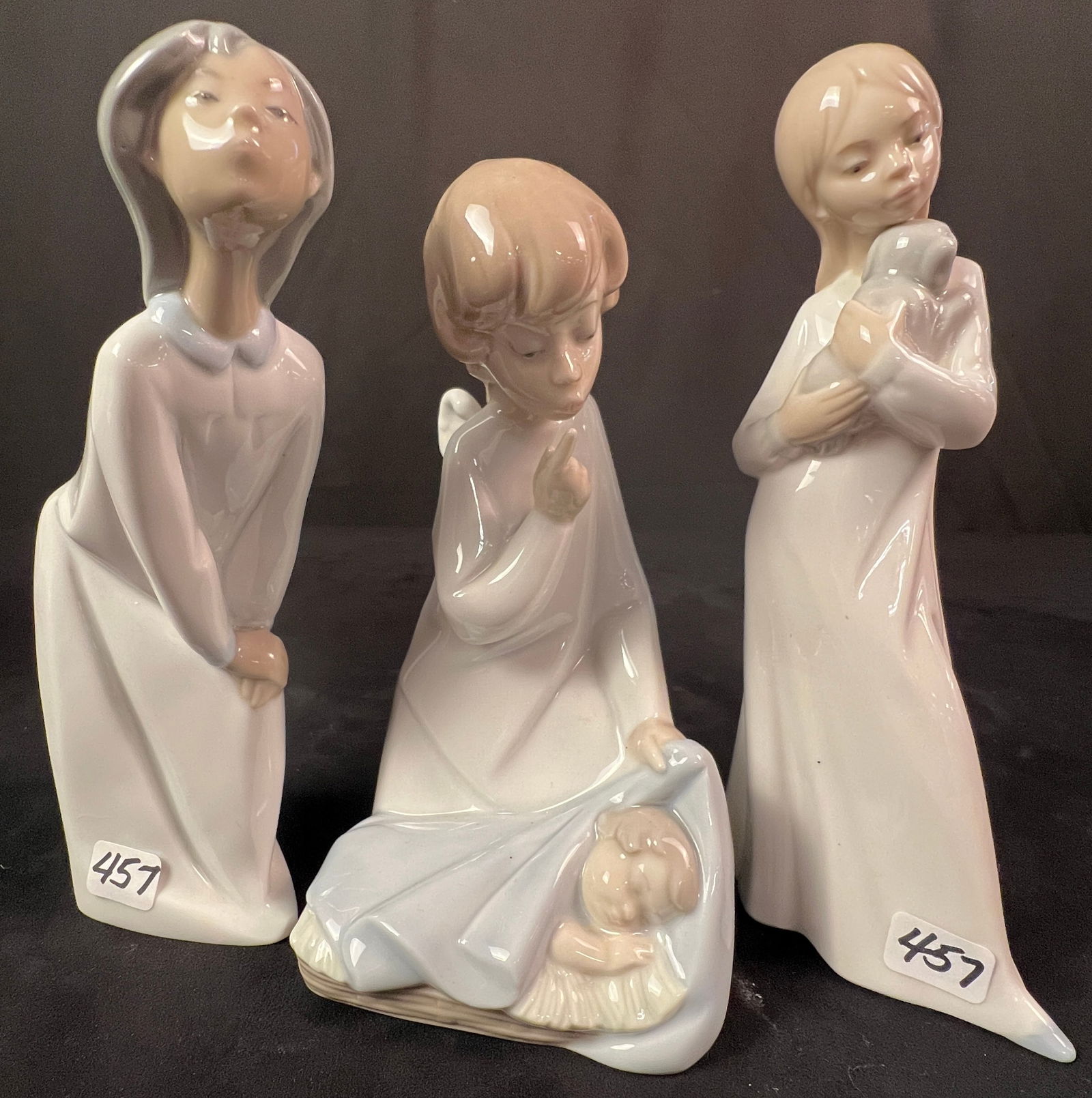 3 Lladro Italian Porcelain Figurines, Angel, Girl w/ Puppy, Kissing Girl: A group of 3 fine porcelain Lladro figurines to include a 7" tall Angel guarding sleeping baby #4635, a Lladro Nao 8" tall girl with dog #0563, and a girl of color kissing #4869. All are signed on the