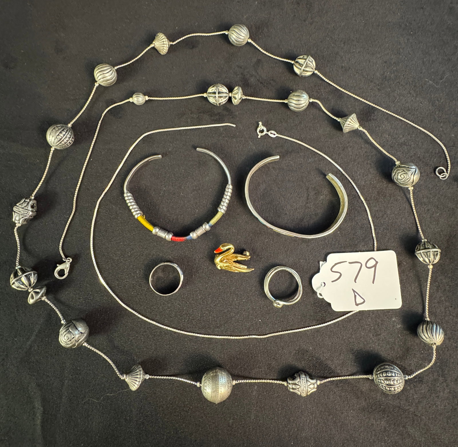Group of Assorted Sterling Jewelry: A group of assorted sterling jewelry to include a large sterling beaded necklace, a box chain necklace, a swan pin, 2 rings and 2 cuff bracelets. Total weight is 85.1 grams.