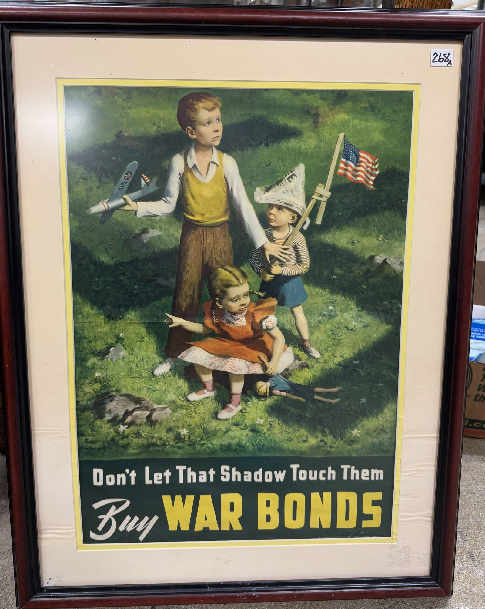 WWll War Bonds Poster c1942: An original quality framed WWII war bonds poster designed by Lawrence Beall Smith depicting 3 American children playing on a lawn under the shadow of a Swastica with the banner "Don't let that shadow