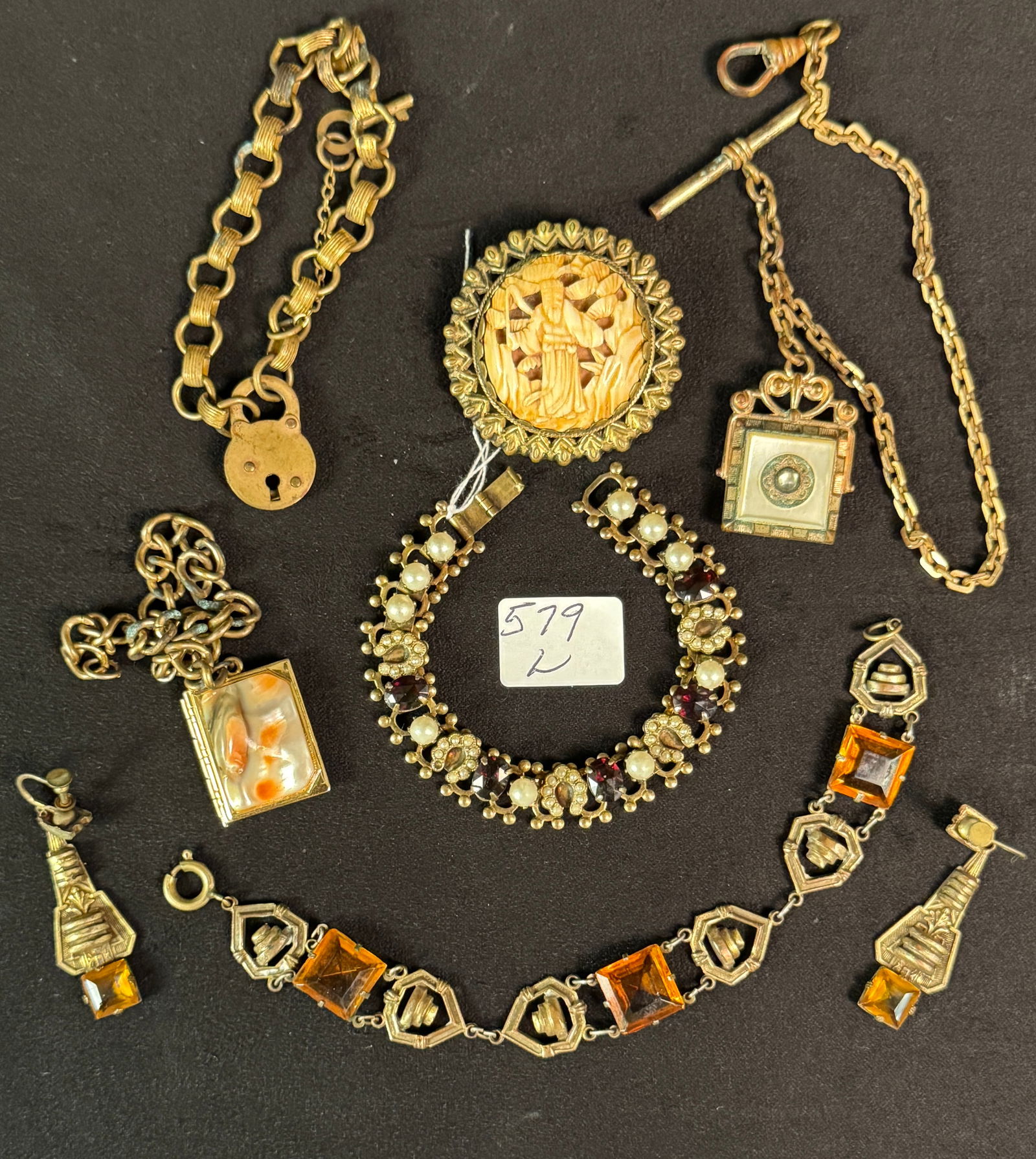 Group of Edwardian Costume Jewelry: Group of Edwardian costume jewelry to include: 3 watch fobs to include a locket, another with a lock and key, and one fancy carnelian; 2 bracelets: a citrine bracelet, and a horseshoe garnet bracelet;