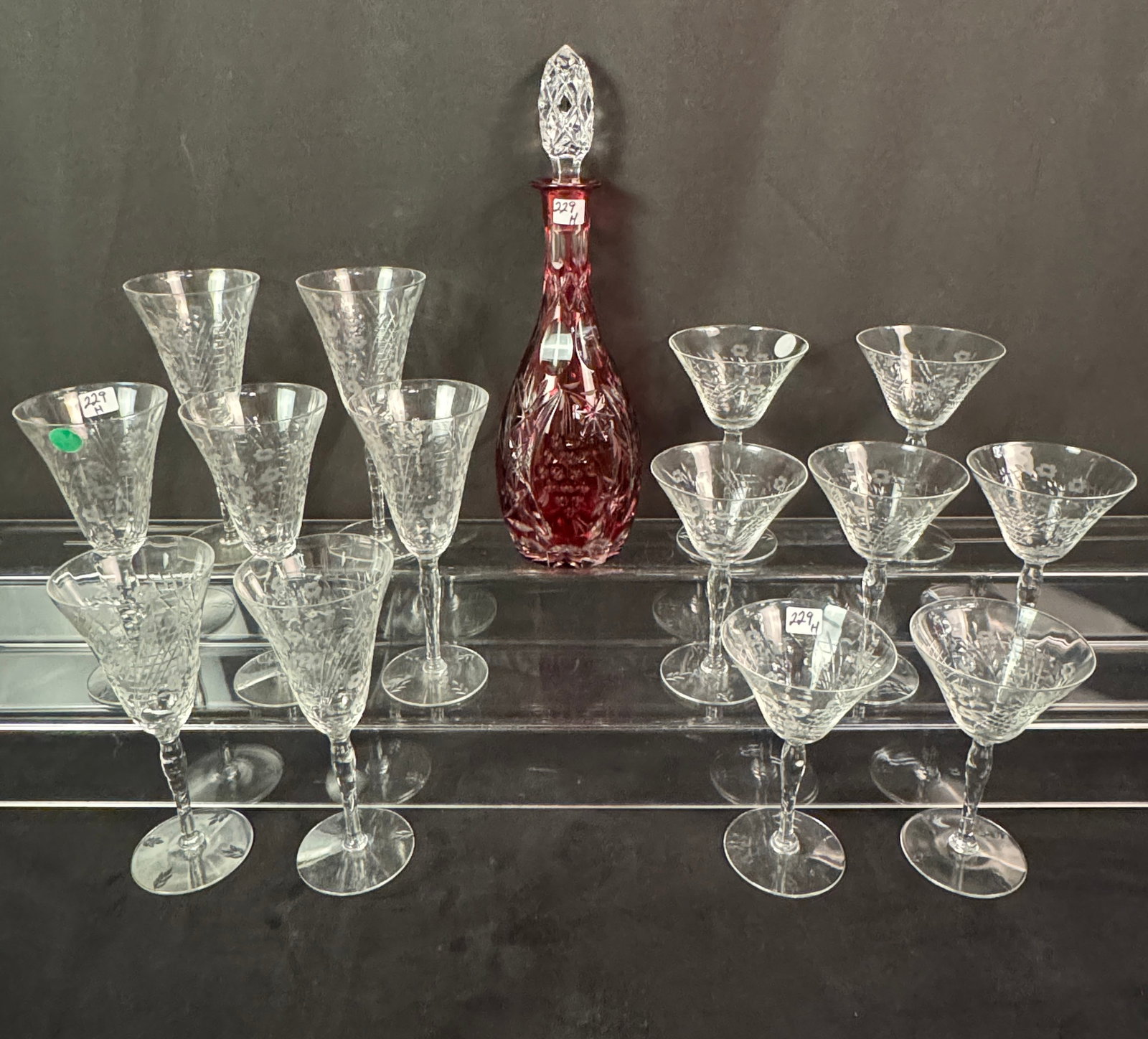 Ruby Cut to Clear Decanter & Stemware: A fancy grape cluster and leaf ruby cut to clear decanter w/stopper, measures 14"h; along with a group of 14 cut and floral etched stems (7 wine glasses, 7 martini glasses). All in excellent condition