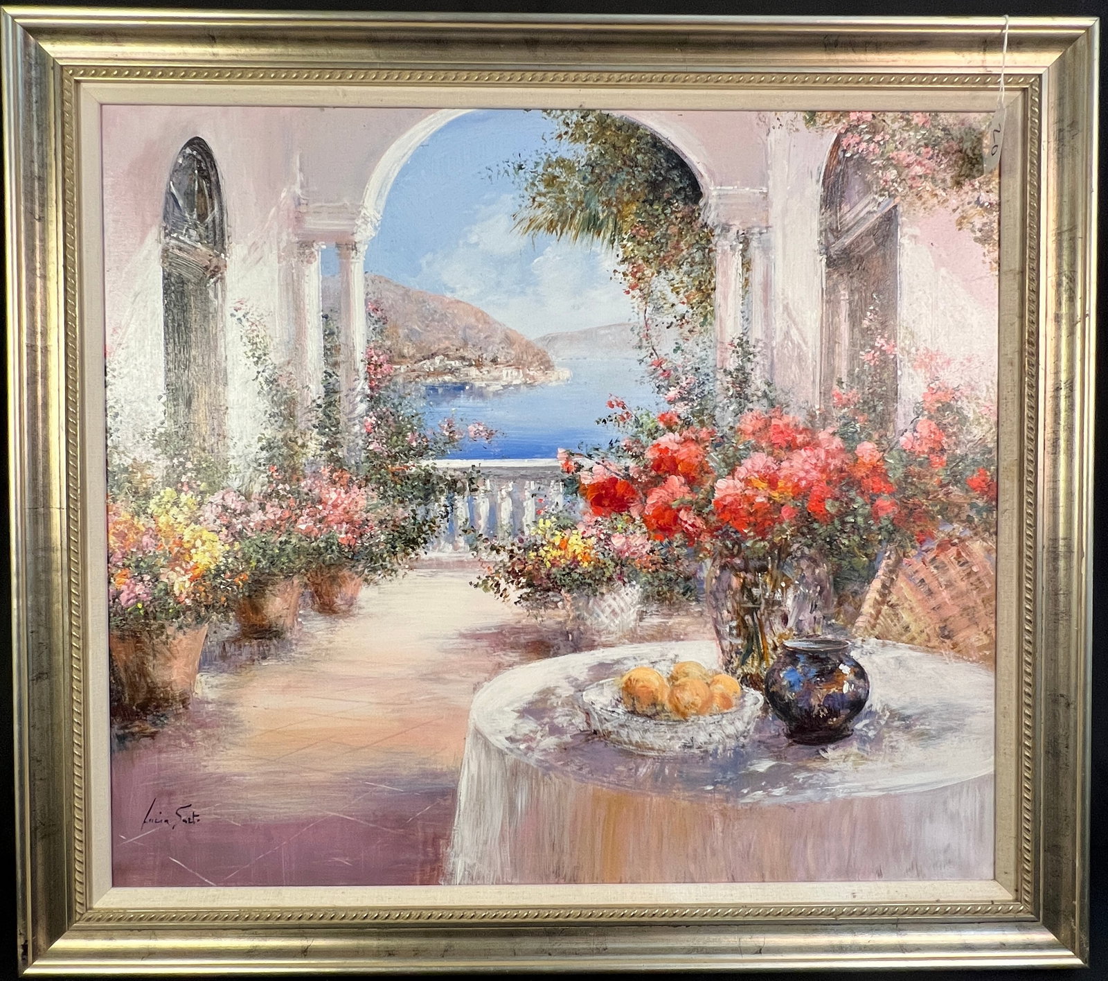 Lucia Sarto Oil on Linen: This quality framed Impressionist style oil on linen still life of flowers is by listed Italian artist Lucia Sarto (1950- ).It features an open air veranda overlooking the sea and flowers in pots vase