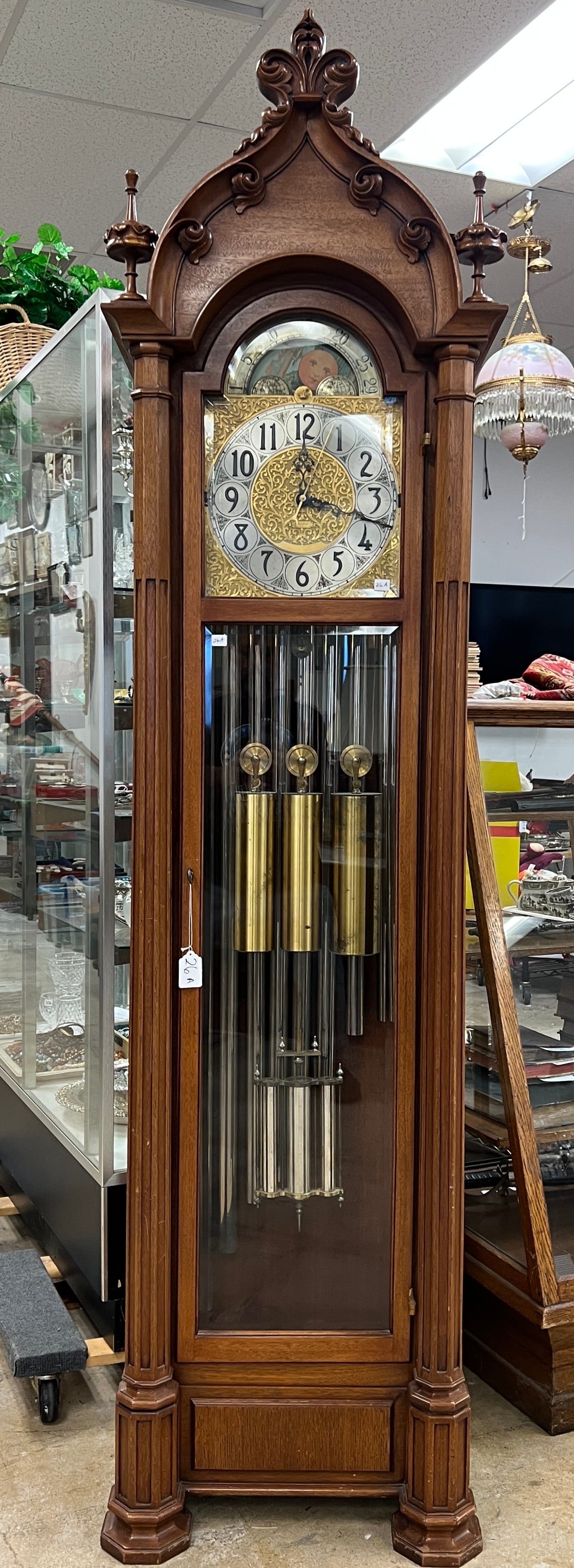 Signed Herschede Gothic Grandfather Clock with Westmister Chimes: A signed Gothic Herschede grandfather clock. This mahogany cased clock features a fleur de lis finial top, pillard front,and beveled glass. 9 tube chime clocks play two melodies, and a phases of the m