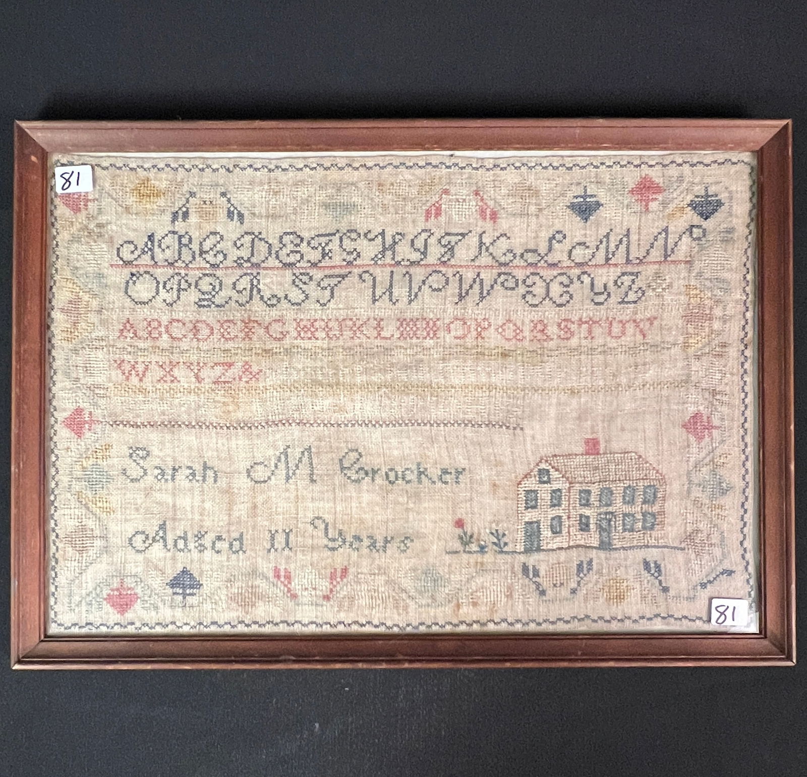 Child's Sampler, Early 1800s: A child's American sampler c.1800/10s, by Sarah M Crocker, aged 11 years. This sampler depicts her country, New England Style saltbox home, with an elaborately decorative border and two styles of the