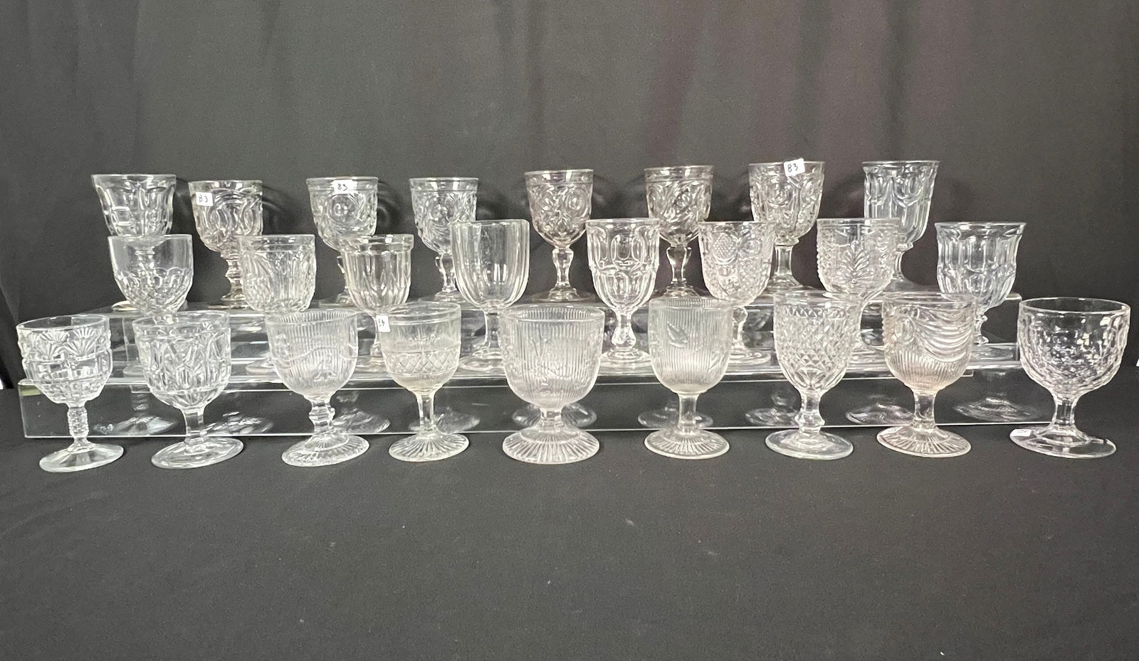 A Group of 25 Flint Glass Goblets c1800's: A large mixed group of 25 antique flint glass goblets c1800's in excellent condition. They each measure approximately 6-6.5" tall. Patterns include "Bull's Eye Fleur -de-lis"," Ashburton"(Boston 7
