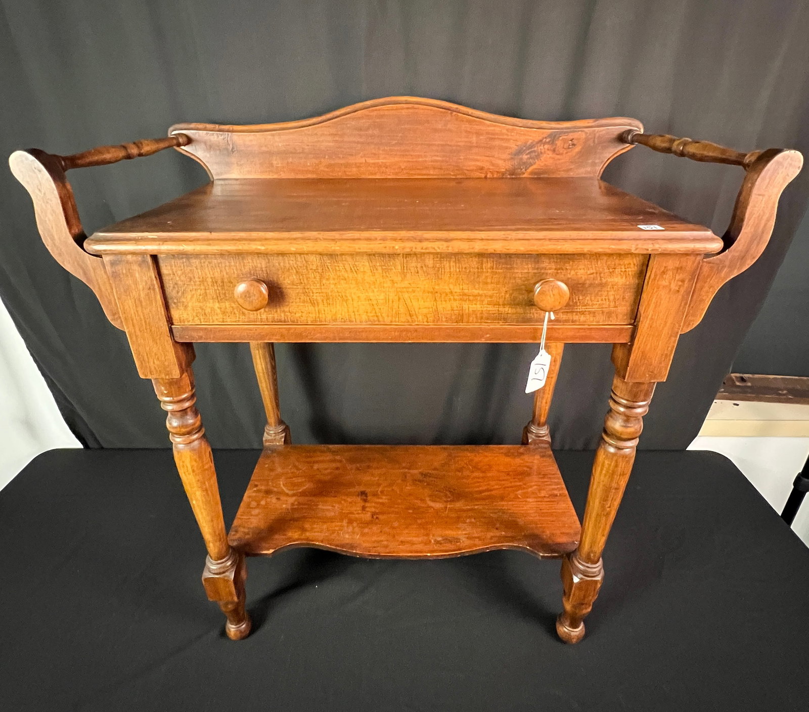 Double Handled, Single Door Washstand, c1880s: A doubled handled, single door washstand c1880s. It features wood pulls, turned legs, serpentine lower shelf, backsplash, and chamfered drawer bottom. It is in good, house ready condition, and