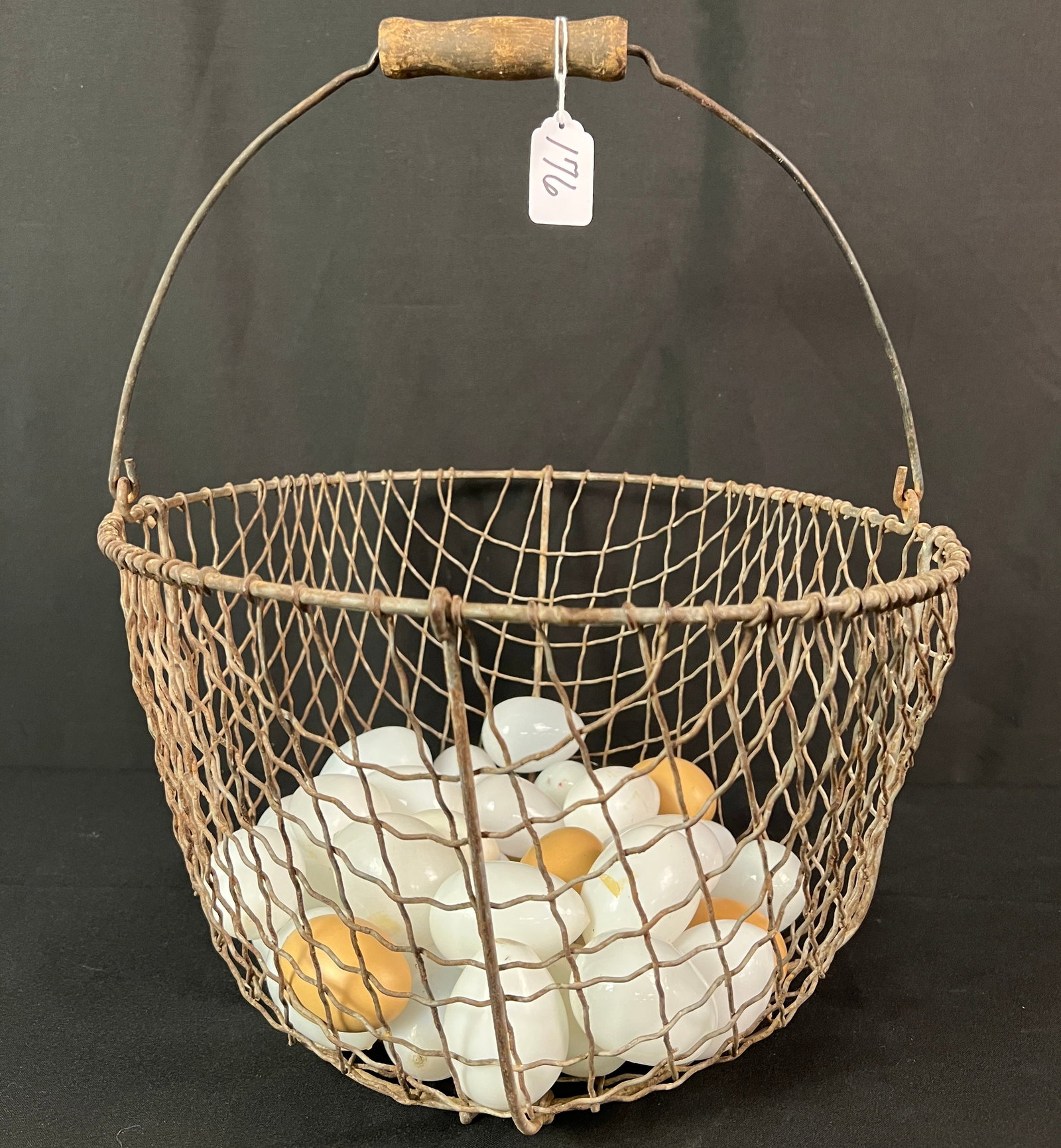 Mesh Bale Handled Egg Basket: A 1900s meshed, bale handled egg basket, filled with glass and wooden eggs. A great display piece, this measures 9" tall X 15" around.