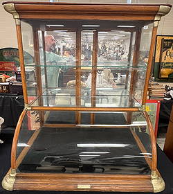 Rare Countertop Display Case by Excelsior Show Case Works: A rare countertop display case featuring a bow front and high top with mirrored sliding back doors. Cabinet features 2 glass shelves. It was made by the Excelsior Show Case Works of Quincy Illinois. I