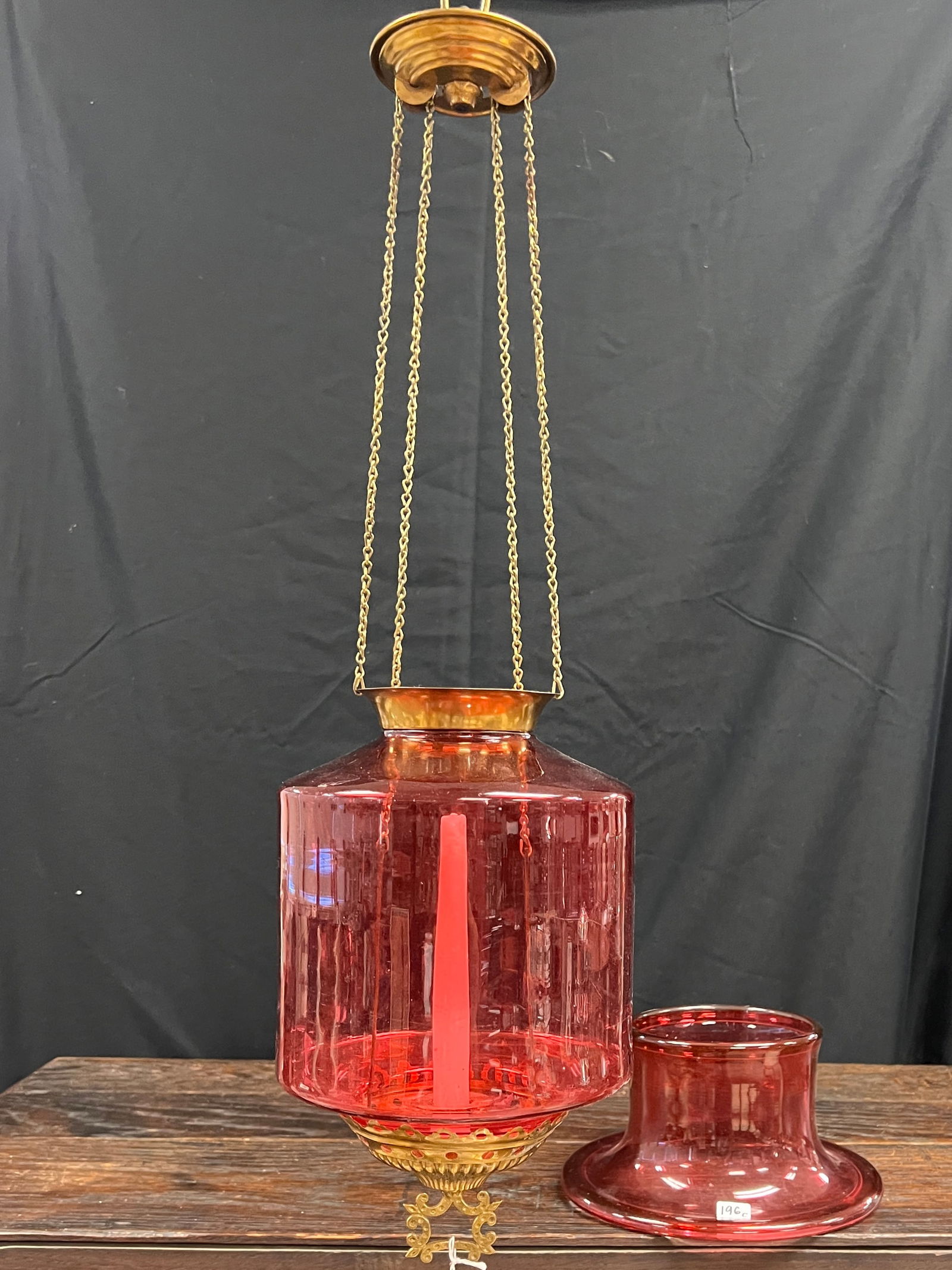 Victorian Cranberry Glass Hanging Candle Light: An antique Victorian cranberry glass hanging candle holder. In a vibrant color with detailed brass hardware, it has not been electrified. In good condition and measures 11" tall X 7" around.