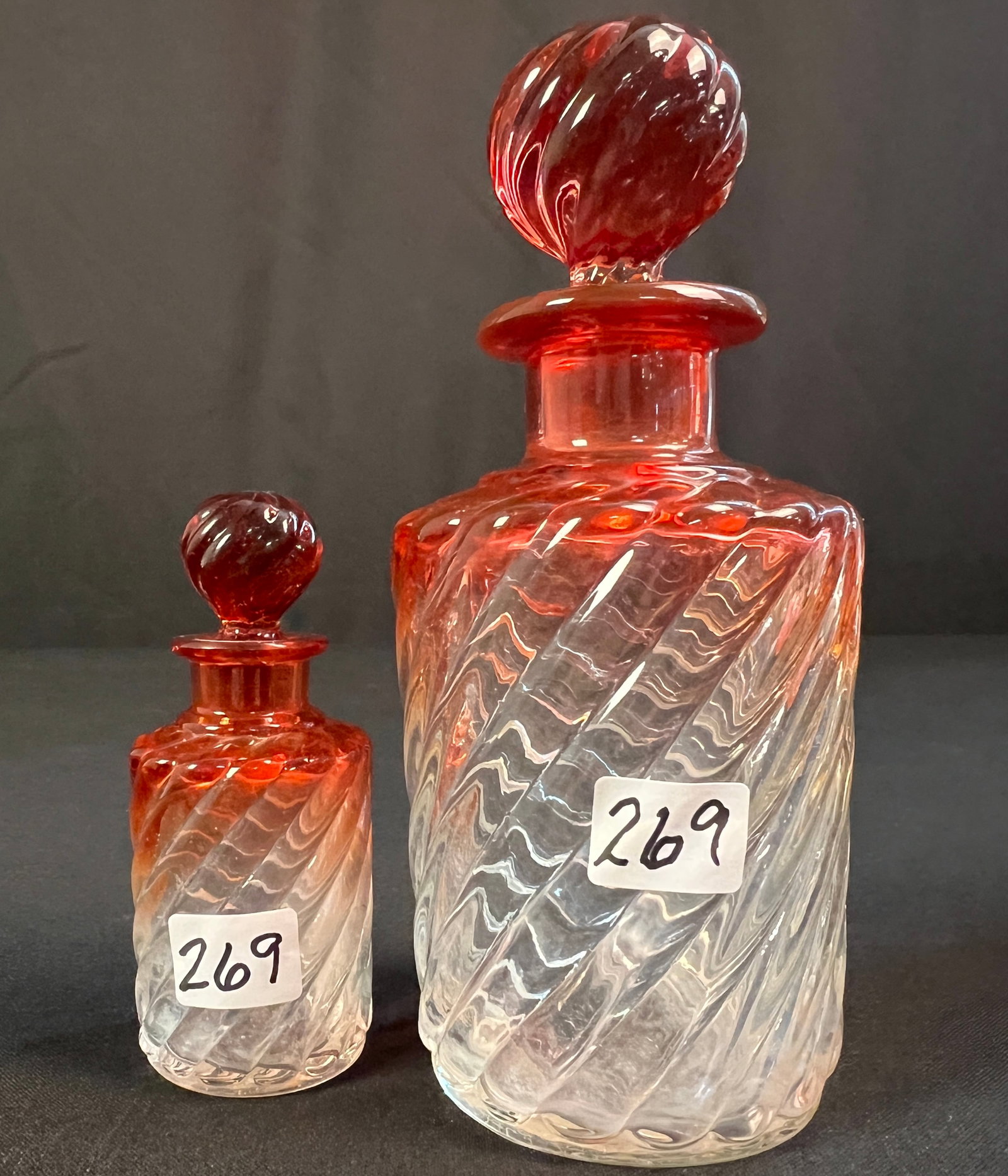 Amberina Art Glass Dresser Bottles: 2 rare barley twist scent bottles in amberina that go from clear to amberina. They retain their original stoppers and are in excellent condition. The large bottle measures 7" tall X 3" across. The