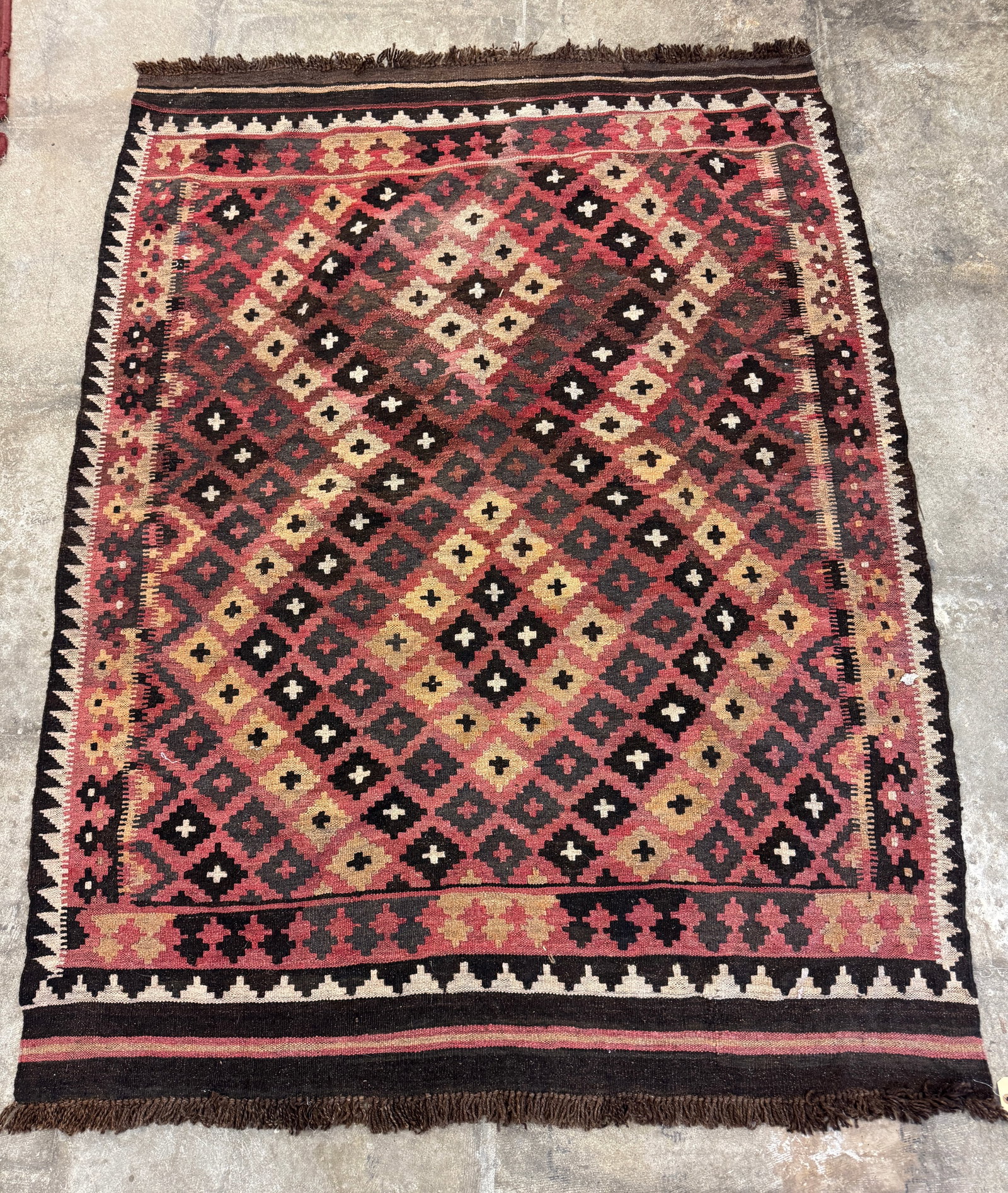 Antique Afghan Maimana Kalim Rug: An antique Afghan Maimana kilim handwoven wool rug featuring geometric patterns in browns, reds, creams and beige. It measures 76" long X 57" across. One good, very old repair along the edge,