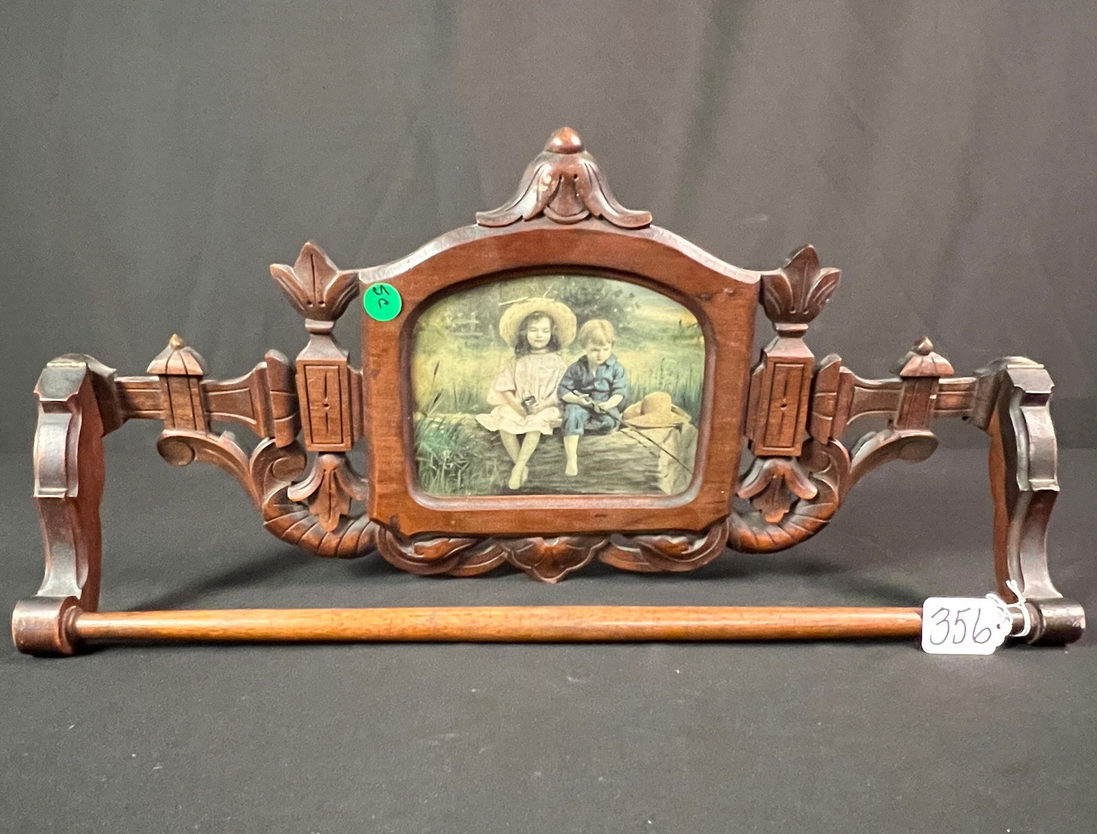Victorian Wall Hung Walnut Towel Rack: A Renaissance Revival walnut Victorian pierced carved and floral wall hung towel rack with portrait center depicting a young boy and girl fishing. This piece came from the G. Heileman brewing estate.