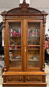 Renaissance Revival Tall Double Door Bookcase: A walnut Victorian Renaissance Revival double door bookcase with drawer base, burled panels, fancy crest and elaborate trims. This double door bookcase has been professionally refinished, retains its