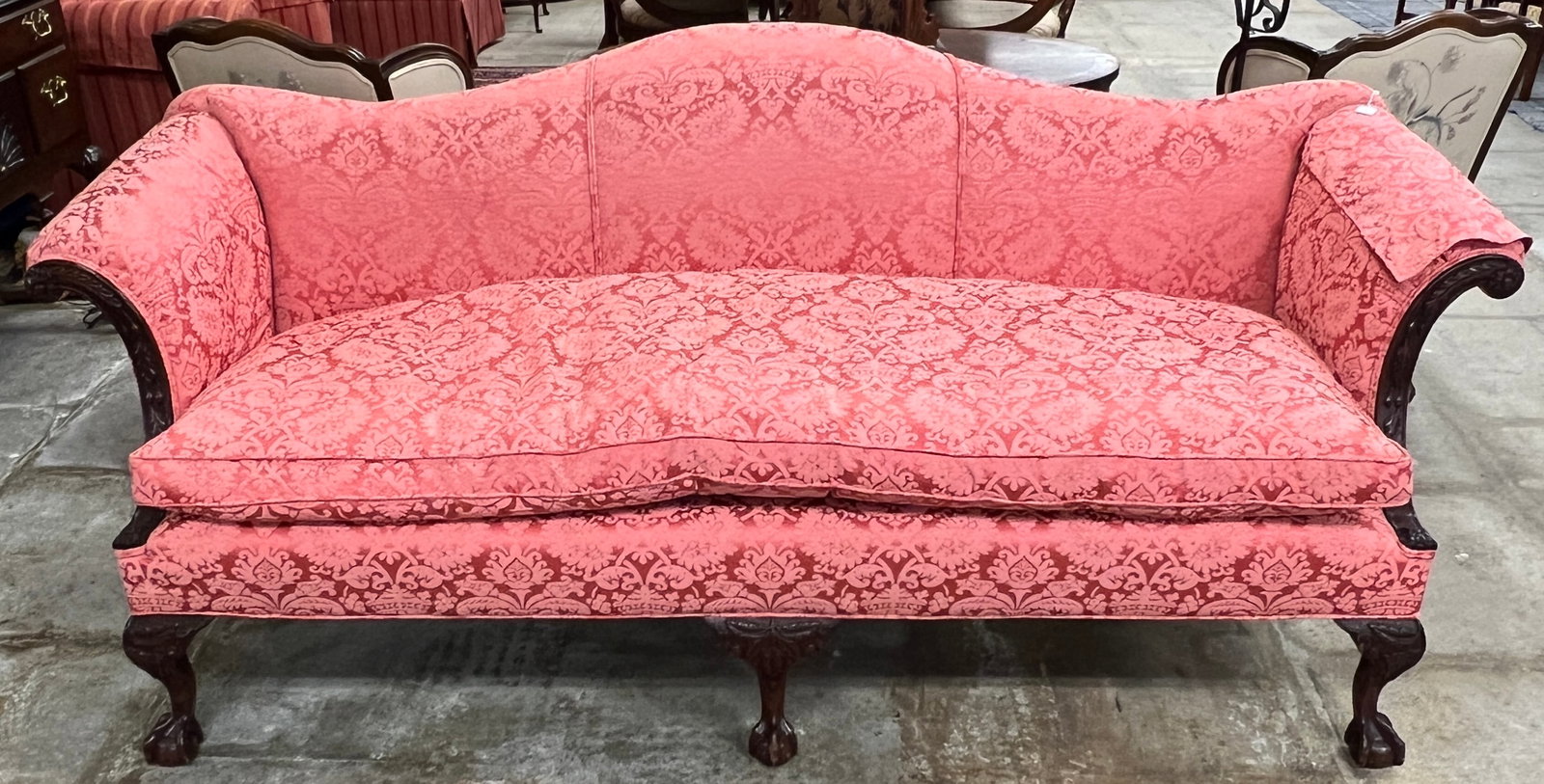 Mahogany Chippendale Sofa: A mahogany Chippendale sofa with tallon and ball feet, scrolled arms, camel back, floral carvings, upholstered in pink silk damask, with a large down cushion. In excellent, house ready condition, it