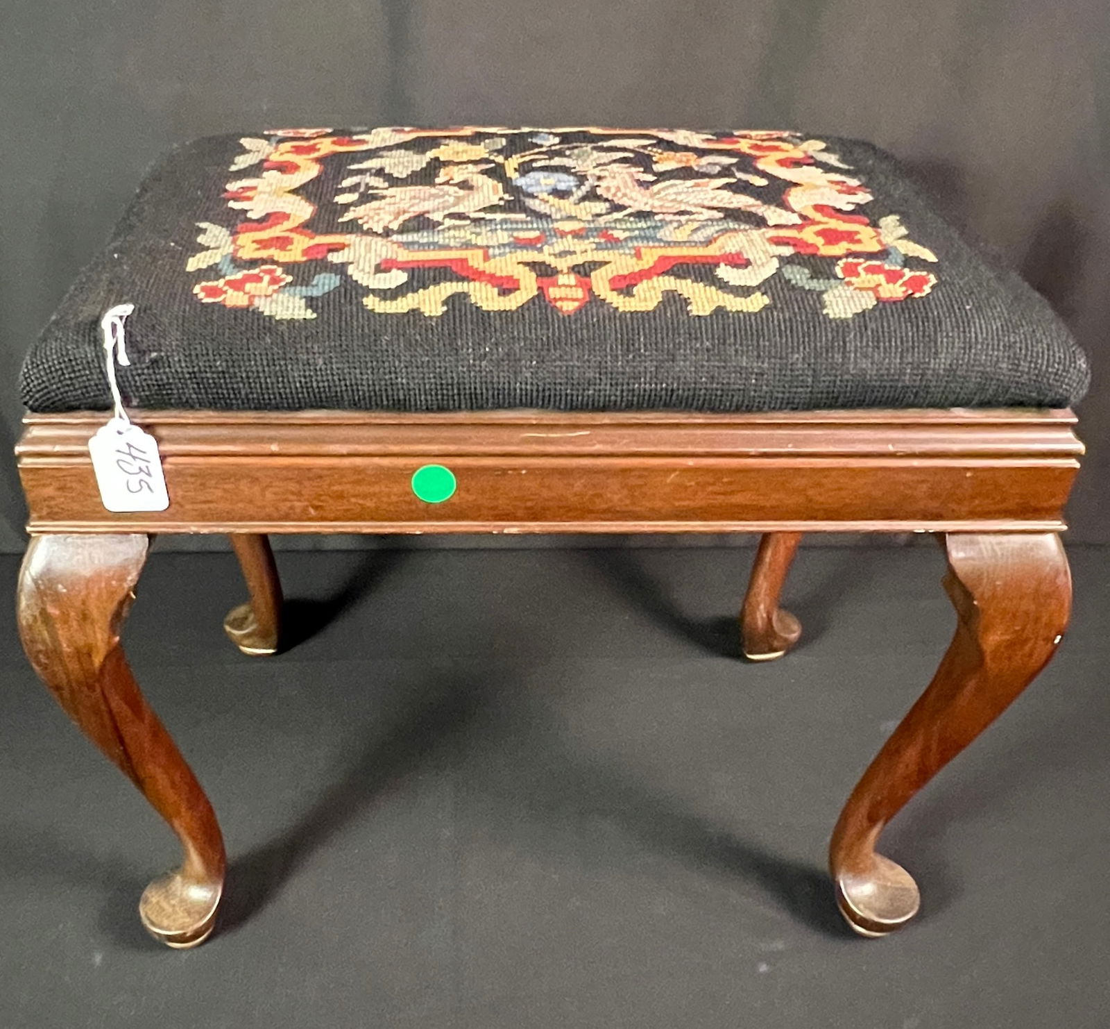Needlepoint Stool: Queen Anne mahogany foot stool with a hand needle point cover depicting birds, flowers and an elaborate border. In excellent, house ready condition, it measures 16" tall X 17" across X 11" deep.