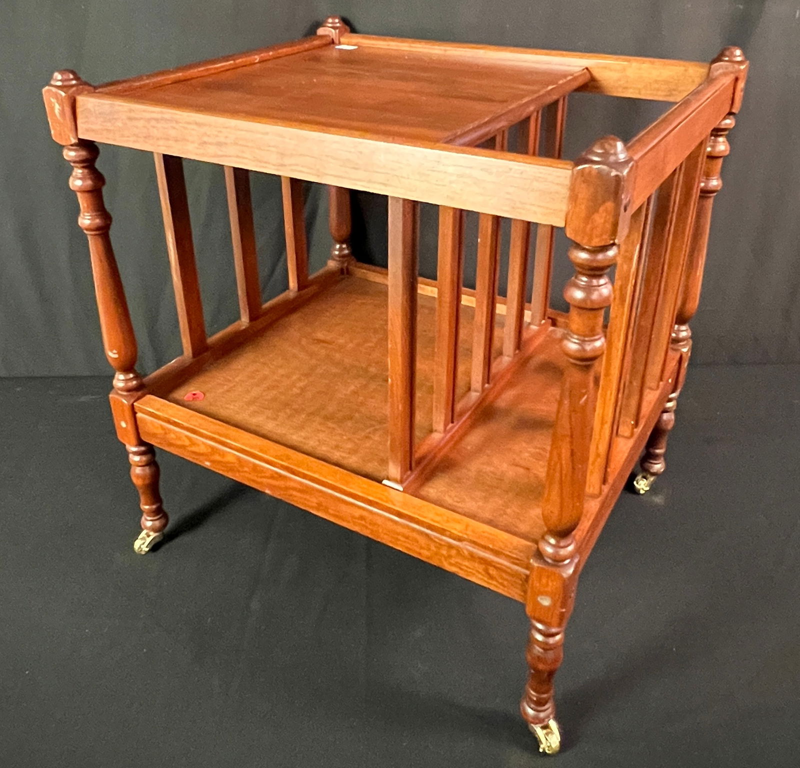 Mahogany Magazine Holder on Rollers: A contemporary quality mahogany two section magazine holder, on brass posts. In good condition, it measures 19" tall X 16" across X 18" deep.