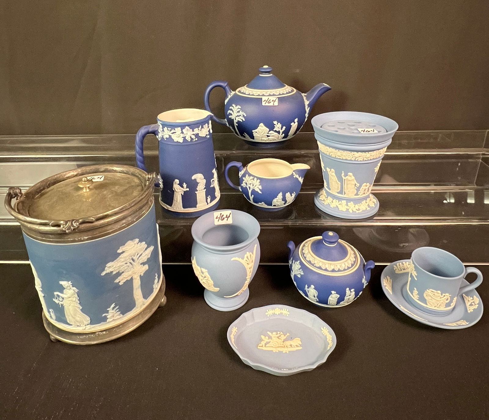 9 Pieces of Blue Wedgewood: A group of 9 blue Wedgewood pieces to include covered biscuit jar depicting Greek goddesses, 3 piece covered tea set depicting Greek goddesses, a large cream pitcher depicting Greek goddesses and