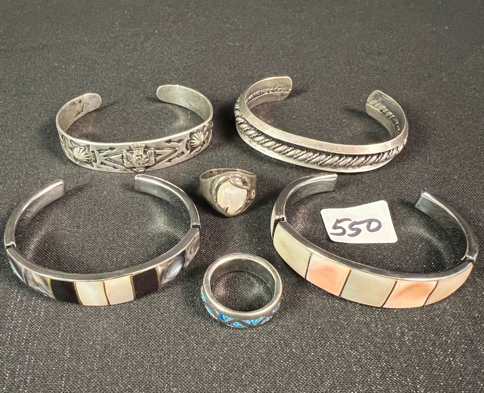 Vintage Group of Bracelets and Rings: A vintage group of bracelets and rings to include a sterling silver Native American cuff bracelet with eagle on it c.1940's (15.29 grams), 2 bracelets inlaid with mother of pearl and shell, a cuff bra