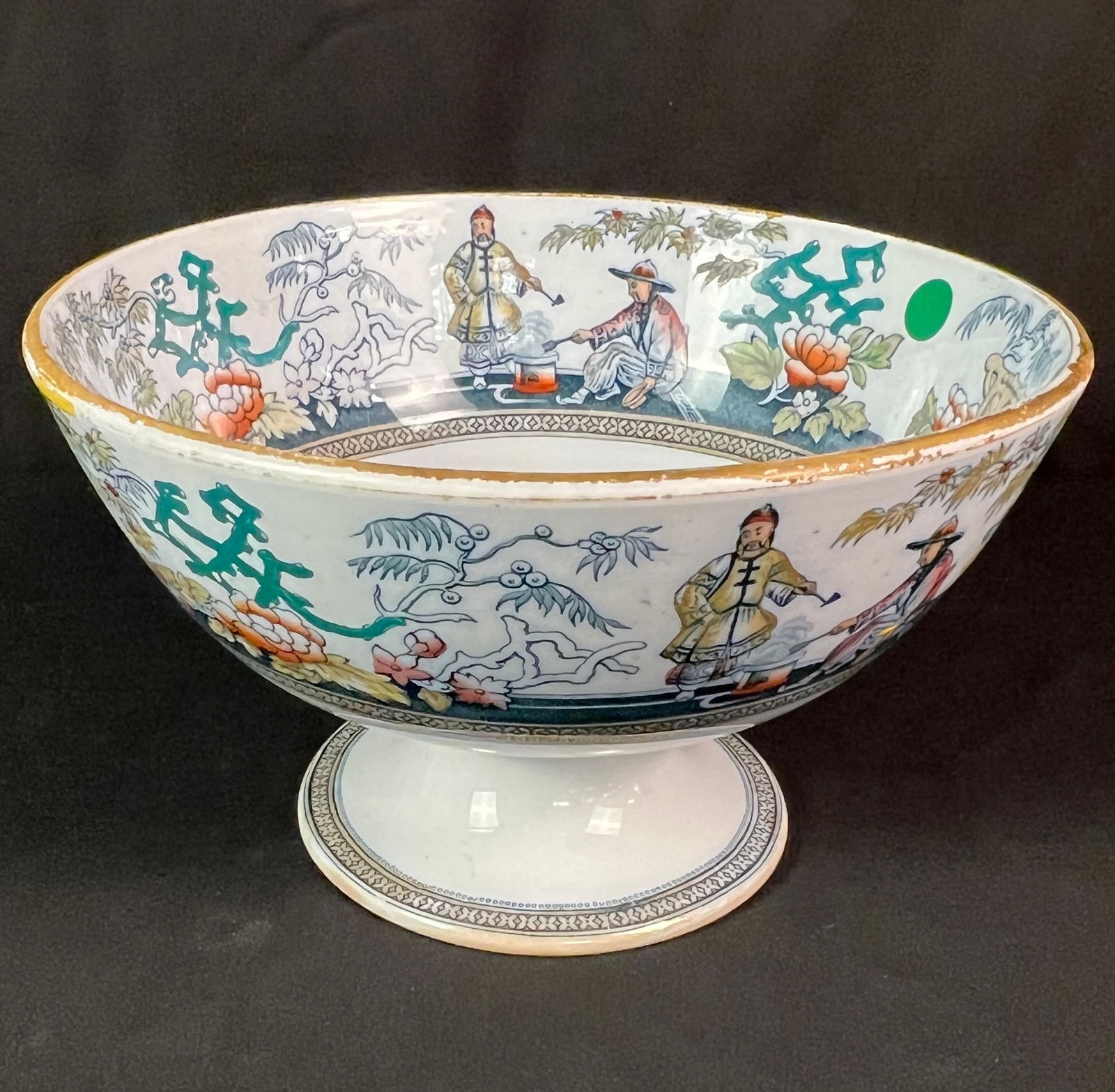 Large Chinese Export Porcelain Bowl: A large antique Chinese Export porcelain punch bowl on a pedestal base. It features hand-painted geometric borders, florals, and a continuous landscape and figural scene. In fair condition with wear o