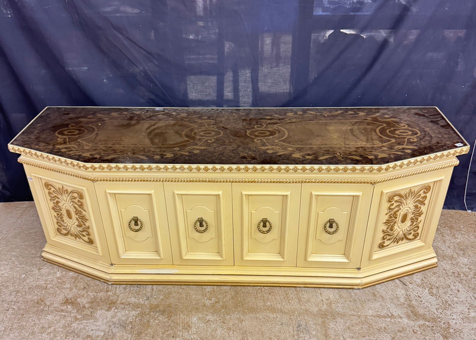 Holllywood Regency Double Door Console C.1966: A Hollywood Regency Mediterranean window chest/double door console with an antique bronze finish,reverse gold leaf glass top, carved apron and gold accented designs by the Majestic Wood Carving Co. C.