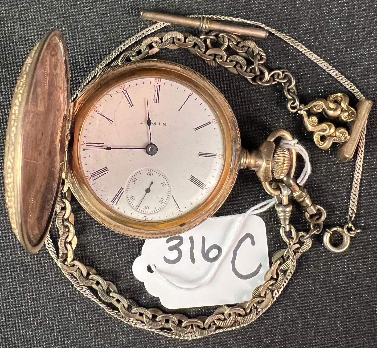 Large Elgin Gold Filled Victorian Pocket Watch: A large Victorian gold filled pocket watch with elaborate chasing, heavy gold filled chains and watch fobs. Watch is complete but does not appear to be in working condition.