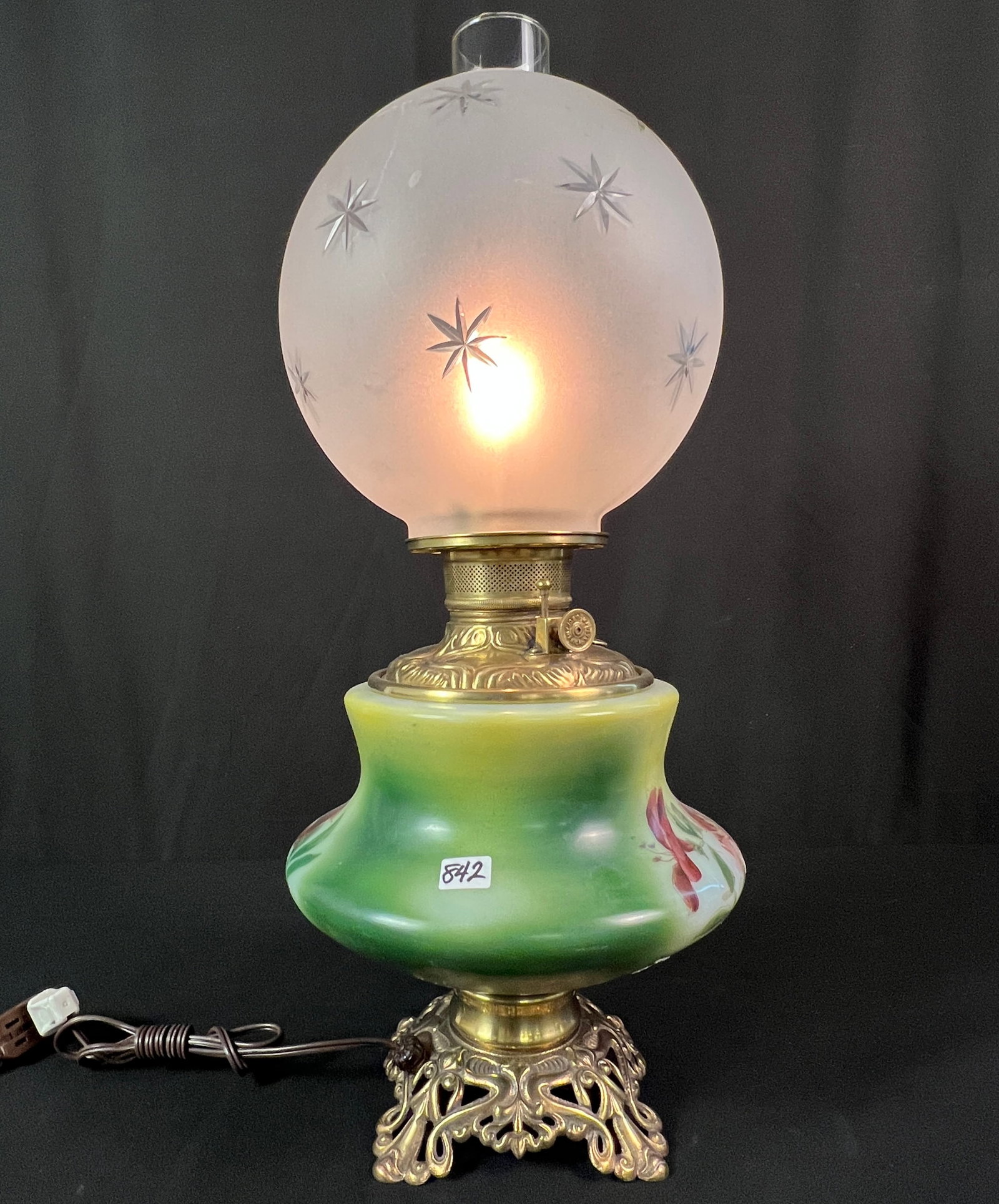 Hand-Painted Gone with the Wind Lamp: A hand-painted Gone with the Wind lamp, with green and floral painted base and a frosted and cut crystal bulbus shade. In working condition, it measures 22" tall X 10" around.