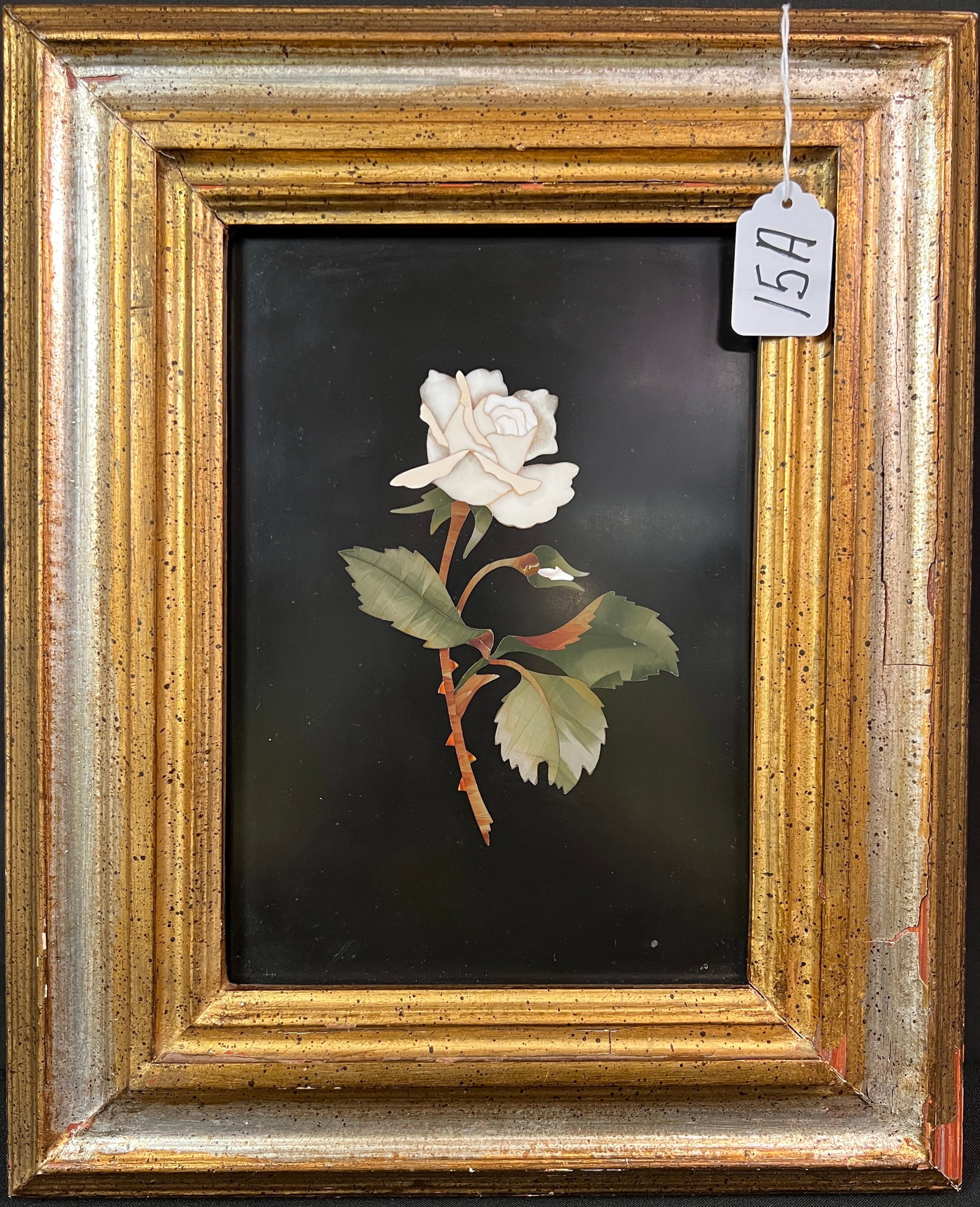 Pietra Dura White Rose on Black Slate: A large pietra dura inlayed white rose with green leaves and brown stem, into a black slate background. This large representation of rose in stone measures 15" tall X 12.5" across framed. In