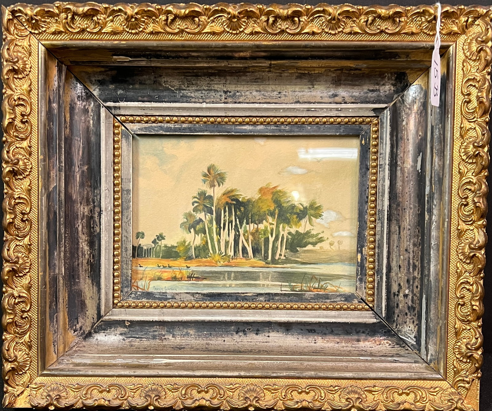 Watercolor of Palm Trees c.1900: A turn of the century elaborately framed watercolor depicting palm trees in a swamp. Artist signed, Carrie Giltner. In great condition with flea bite to corner of frame, it measures 11.5" tall X 14"