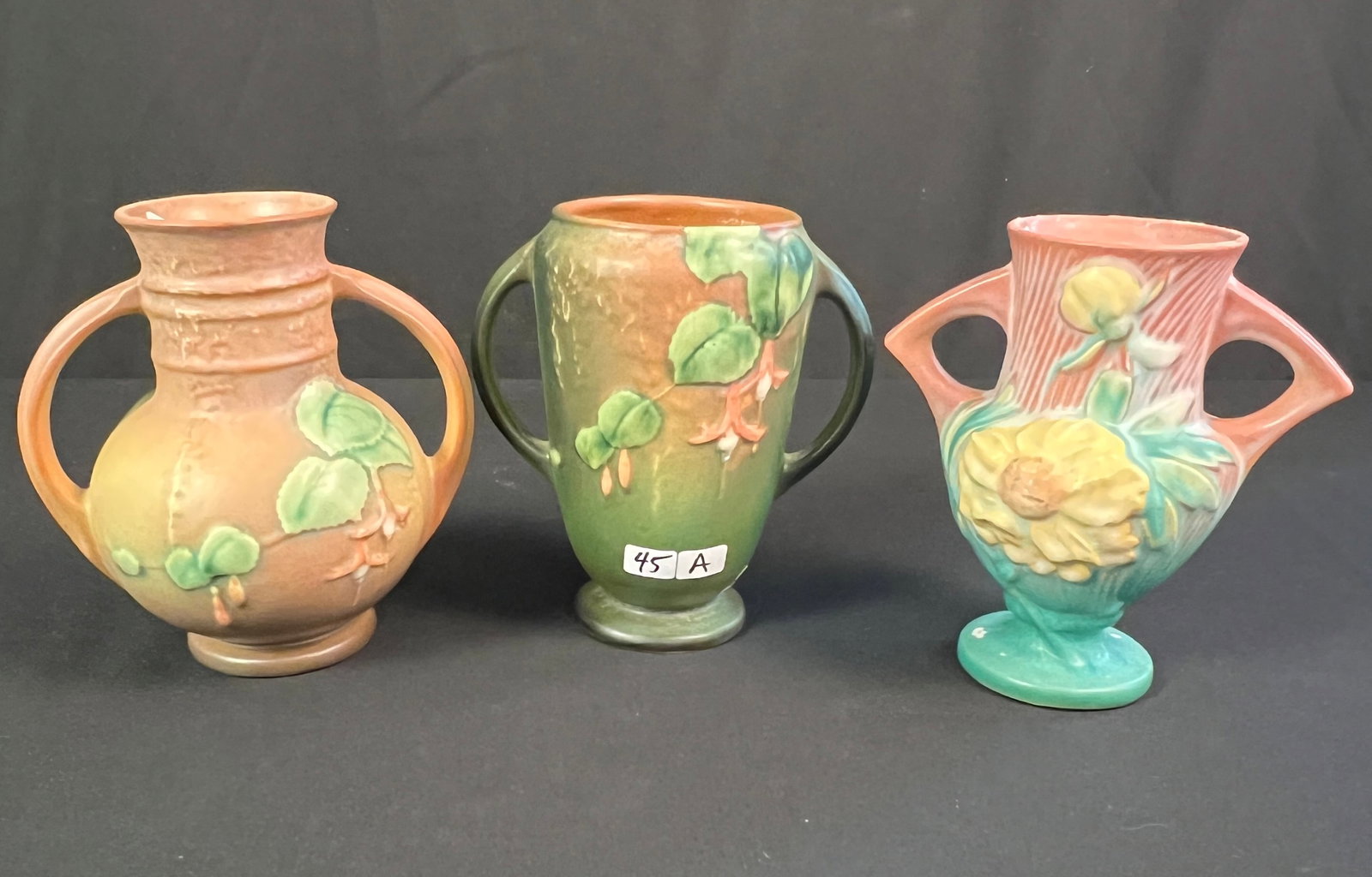 2 Pieces of Fuchsia Roseville Pottery and Peony Vase: Two pieces of Roseville pottery in the Fuchsia pattern, both vases are double handed and measure approximately 6.5" tall. One vase has a crack noted. Also included is a two-handled Peony Vase in excel
