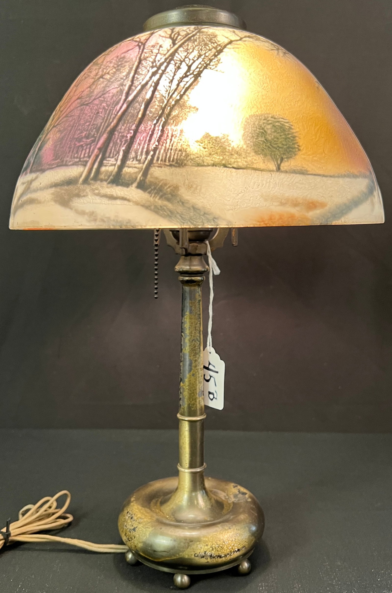 Winter Scene Reverse Painted Lamp: A turn of the century reverse painted lamp with a winter scene depicted on shade. Glass features a chipped frosted texture, lamp is likely attributed to The Pittsburgh Lamp Company. It measures 19.5" 