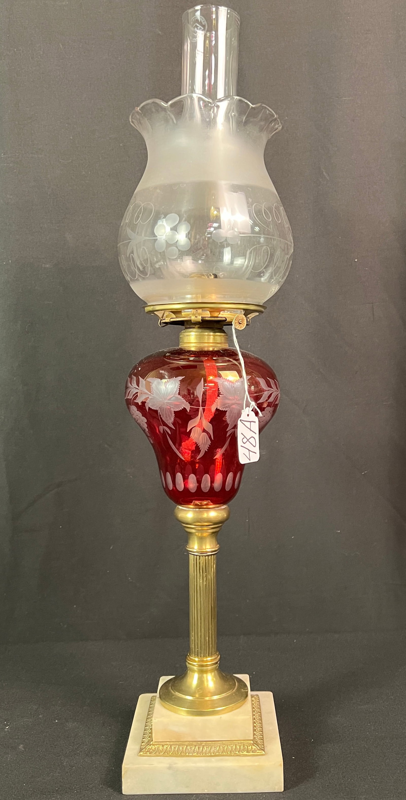 Ruby Cut Oil Lamp: A ruby cut to clear oil lamp fount on a brass Pillard and marble base, with its original floral and frosted shade, with signed hurricane. In excellent all original condition, it measures 26" tall.