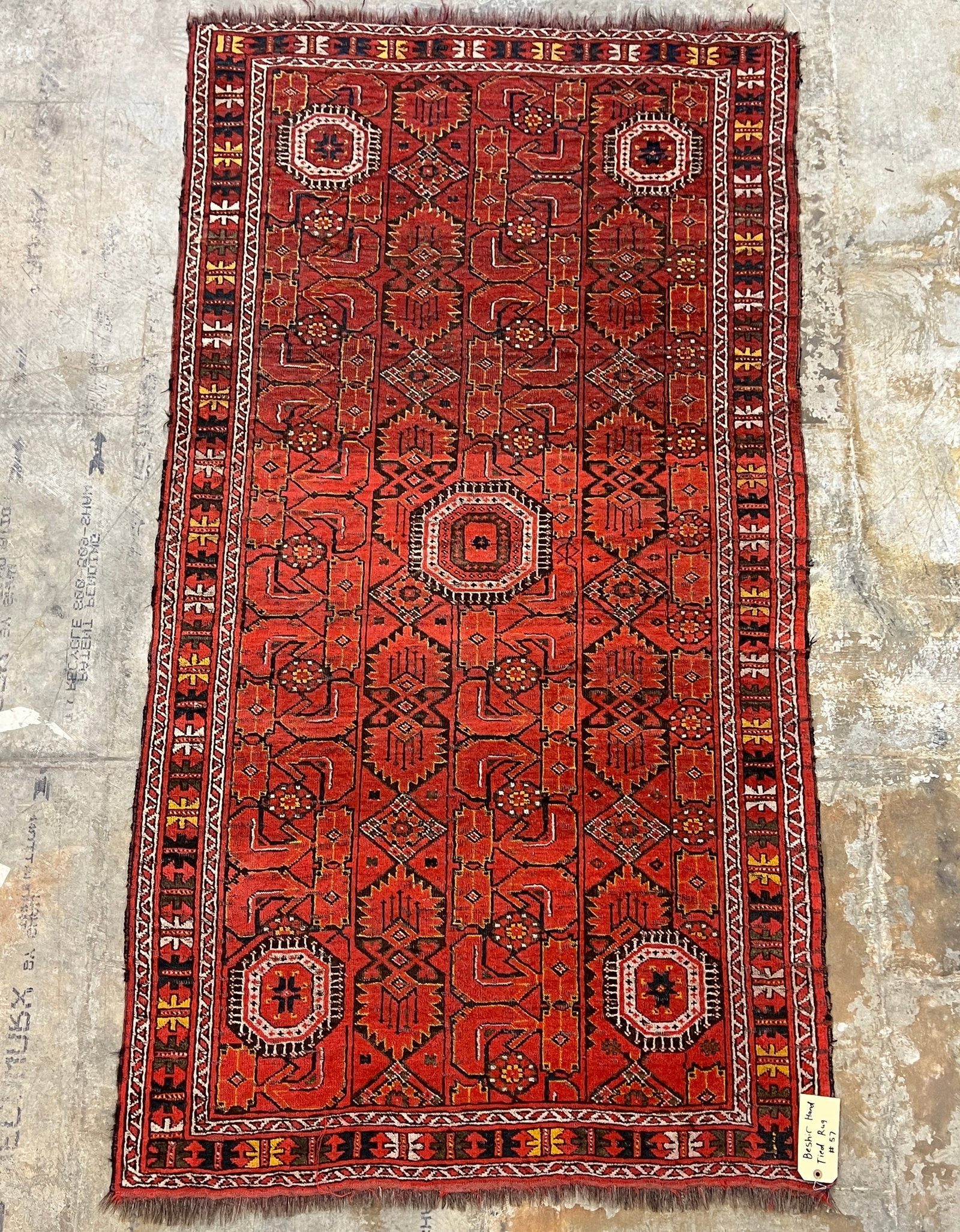 Hand Tied Beshir Wool Rug: A hand tied Beshir wool rug featuring bold geometric patterns, retains original fringe and features symmetrical Turkish knotting. This rug is done primarily in reds, but also features yellows, blues,