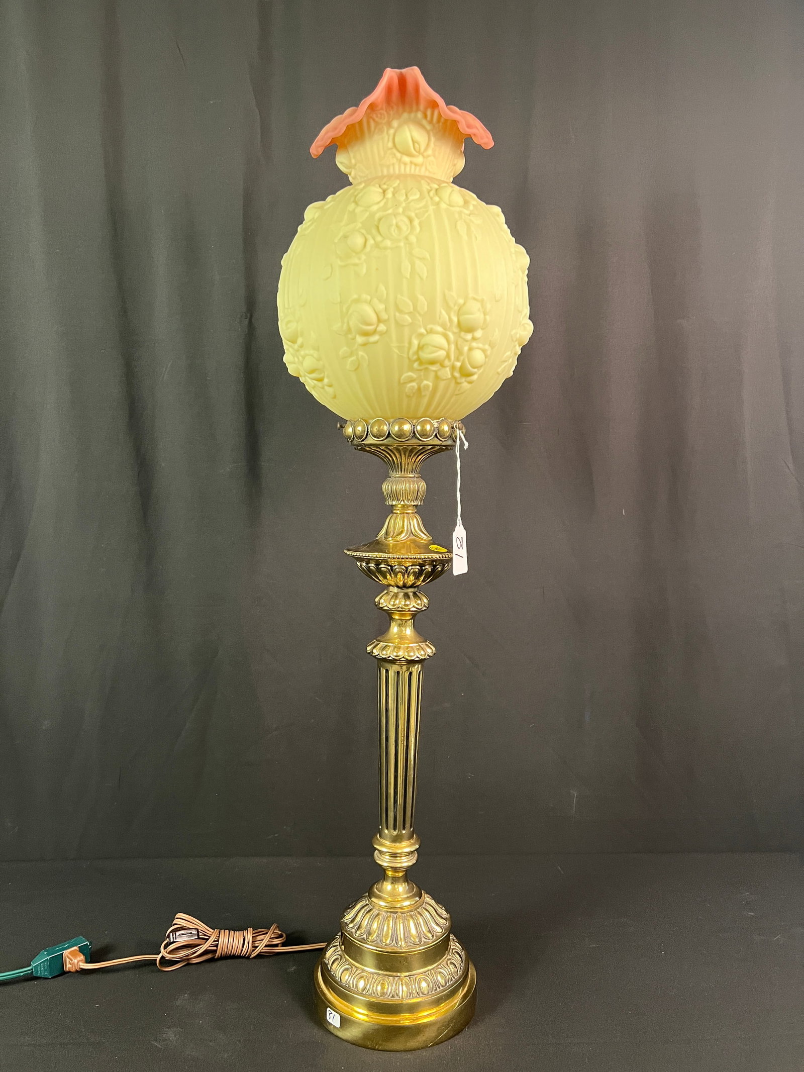 Fenton Banquette Lamp w/Burmese Glass Shade: An electrified Fenton brass gone with the wind style banquette lamp with a Burmese glass round shade in the "Cabbage Rose" pattern. In Excellent condition, it measures 38" tall 9.5" across.