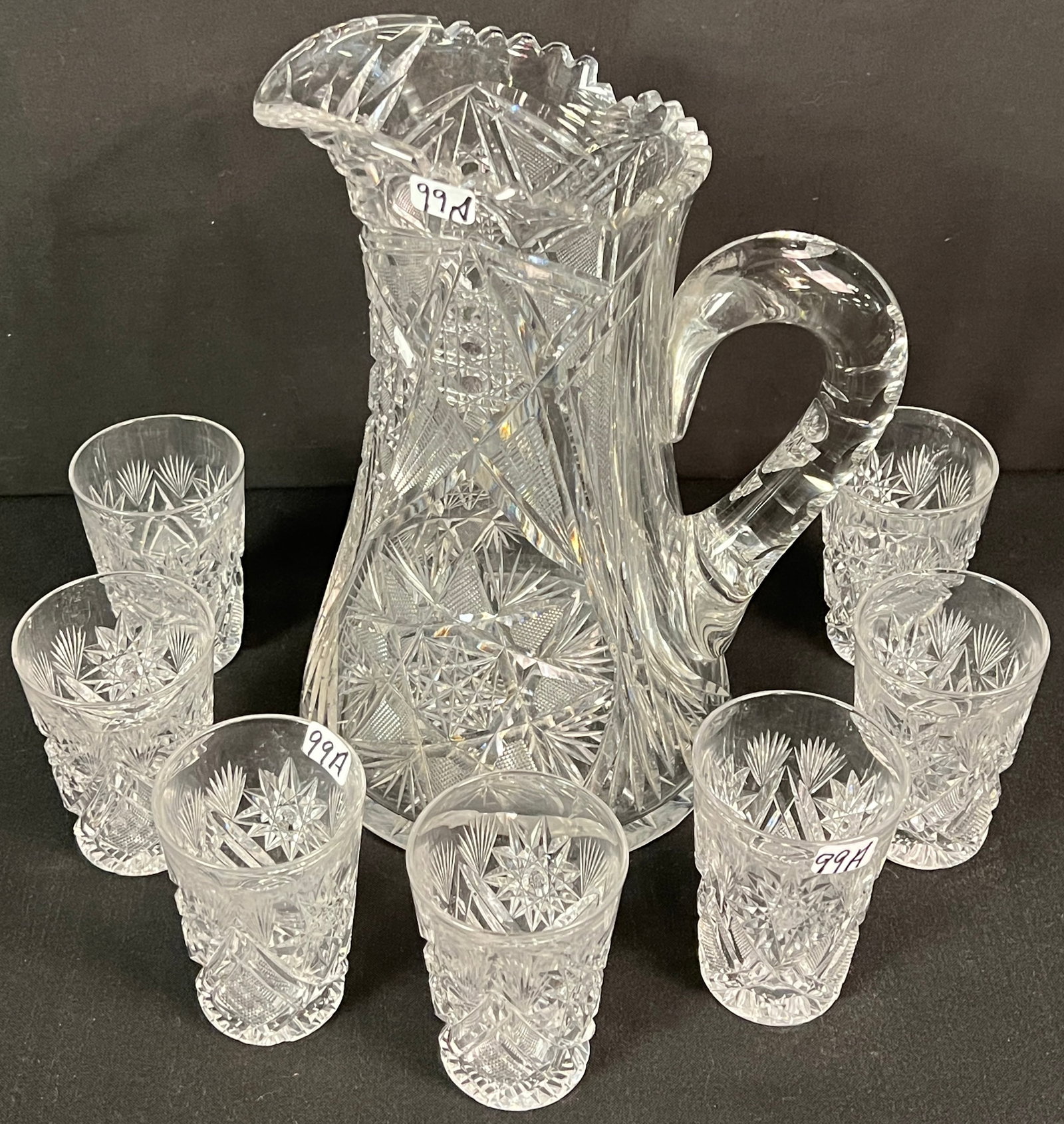Cut Glass Lemonade Pitcher & Tumblers: A brilliant cut glass lemonade pitcher along with 9 cut glass tumblers. All in excellent condition, two tumblers have flea bites on the rim, the pitcher measures 10" tall and the tumblers measure 3.75